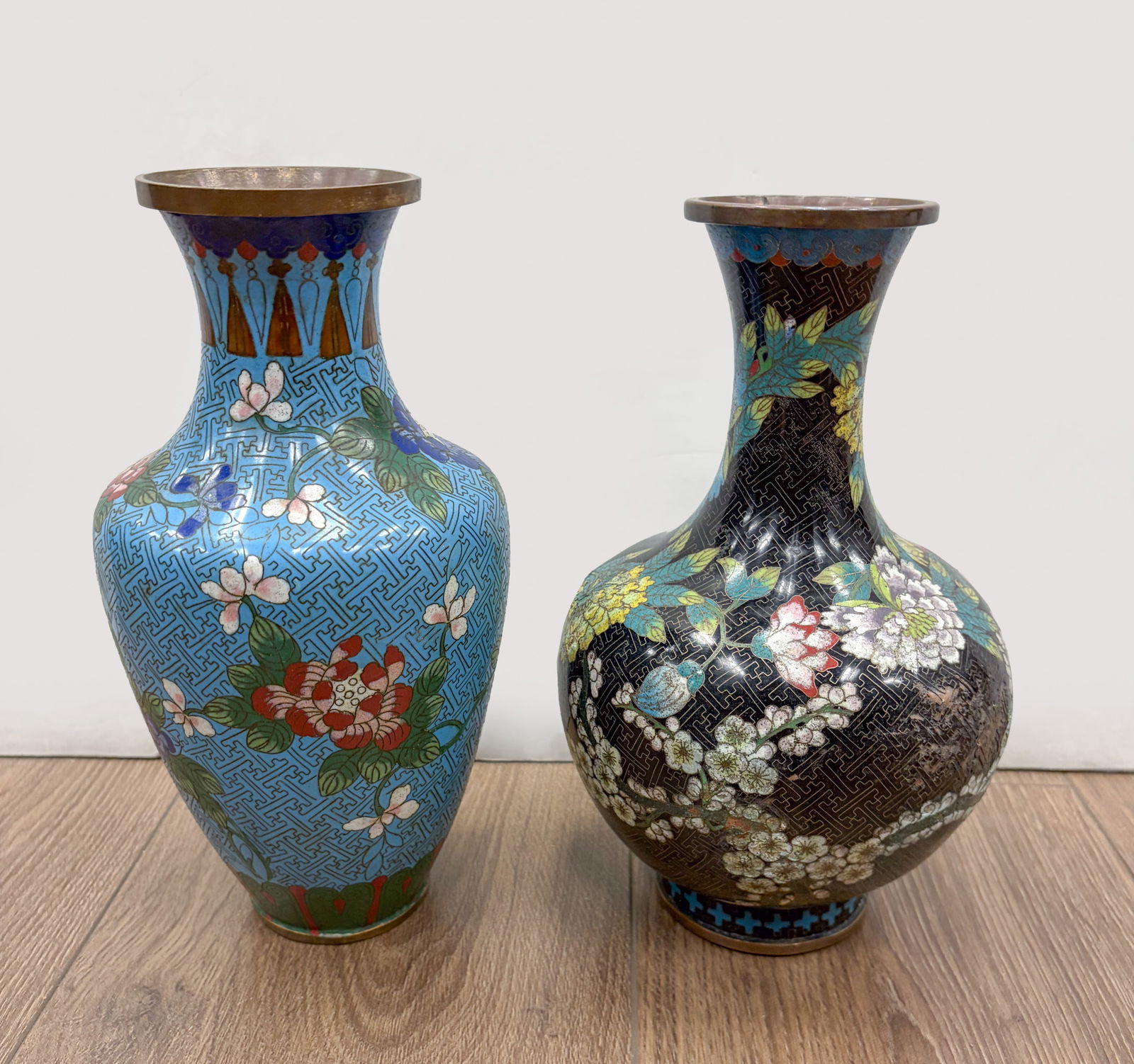 Early 1900s Chinese Cloisonne Vases: Two vintage cloisonne vases, one enameled with various blossoming flowers on black glazed fret body, the other enameled with flowers on turuqoise-blue glazed body. Approx. 9.7*6.1 inch (larger).