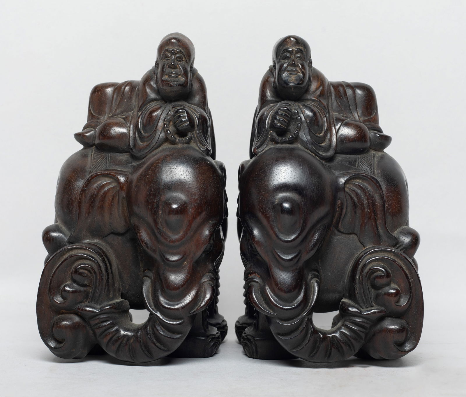 Two Chinese Tan Wood Sculptures: Each carved with Buddha seated on a standing elephant, the Buddha holding prayer beads in hands, the elephant nose spraying water. Approx. 3*2.9*5.3 inch (each). The Estate of the J & J Found, AZ, 202