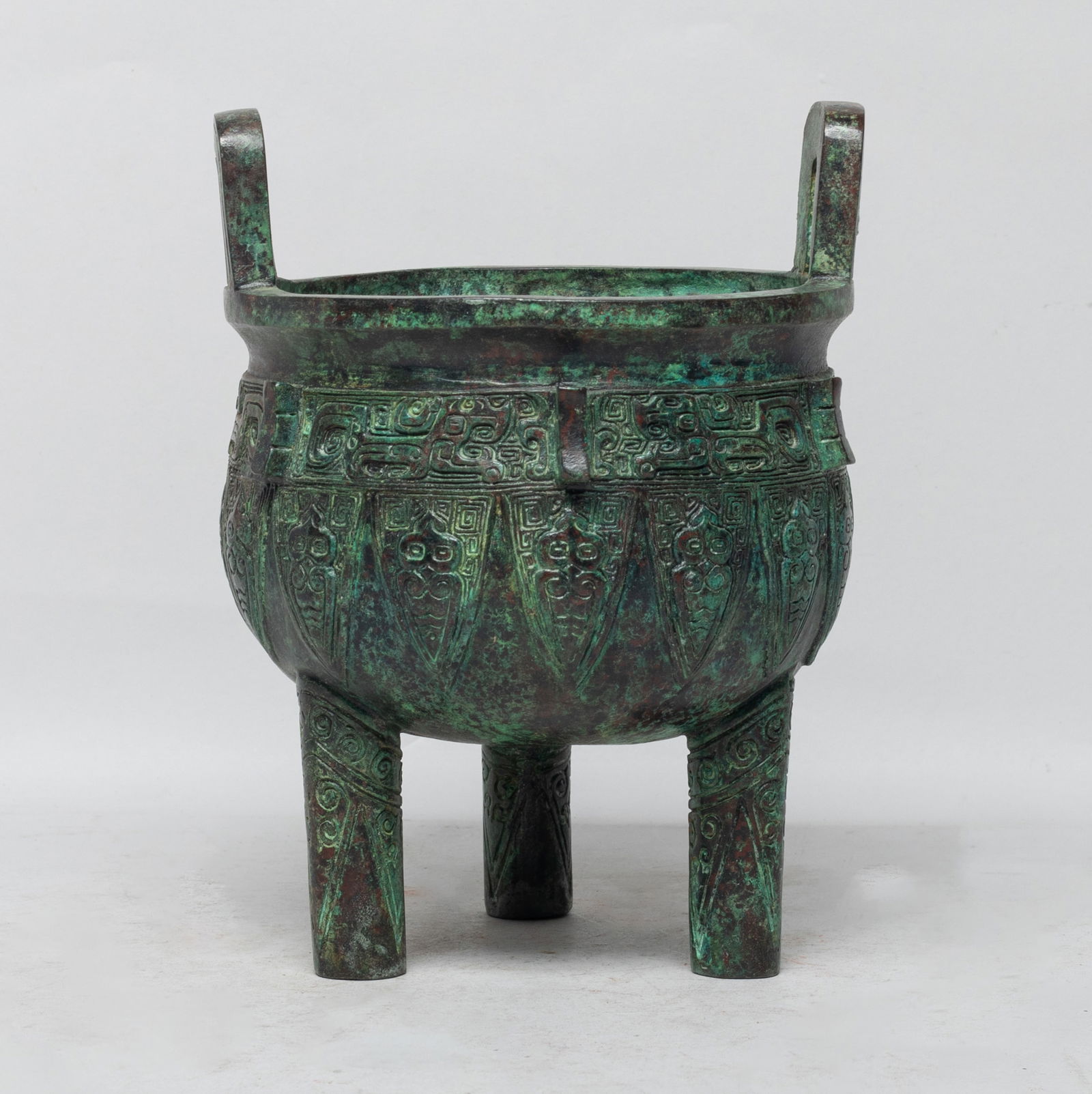 Estate Chinese Bronze Sculpture of Ding: The deep U-shaped body supported on three cylindrical legs, surmounted with two upright handles, the body exterior cast with a band of archaistic beasts divided by raised flanges, below with downward