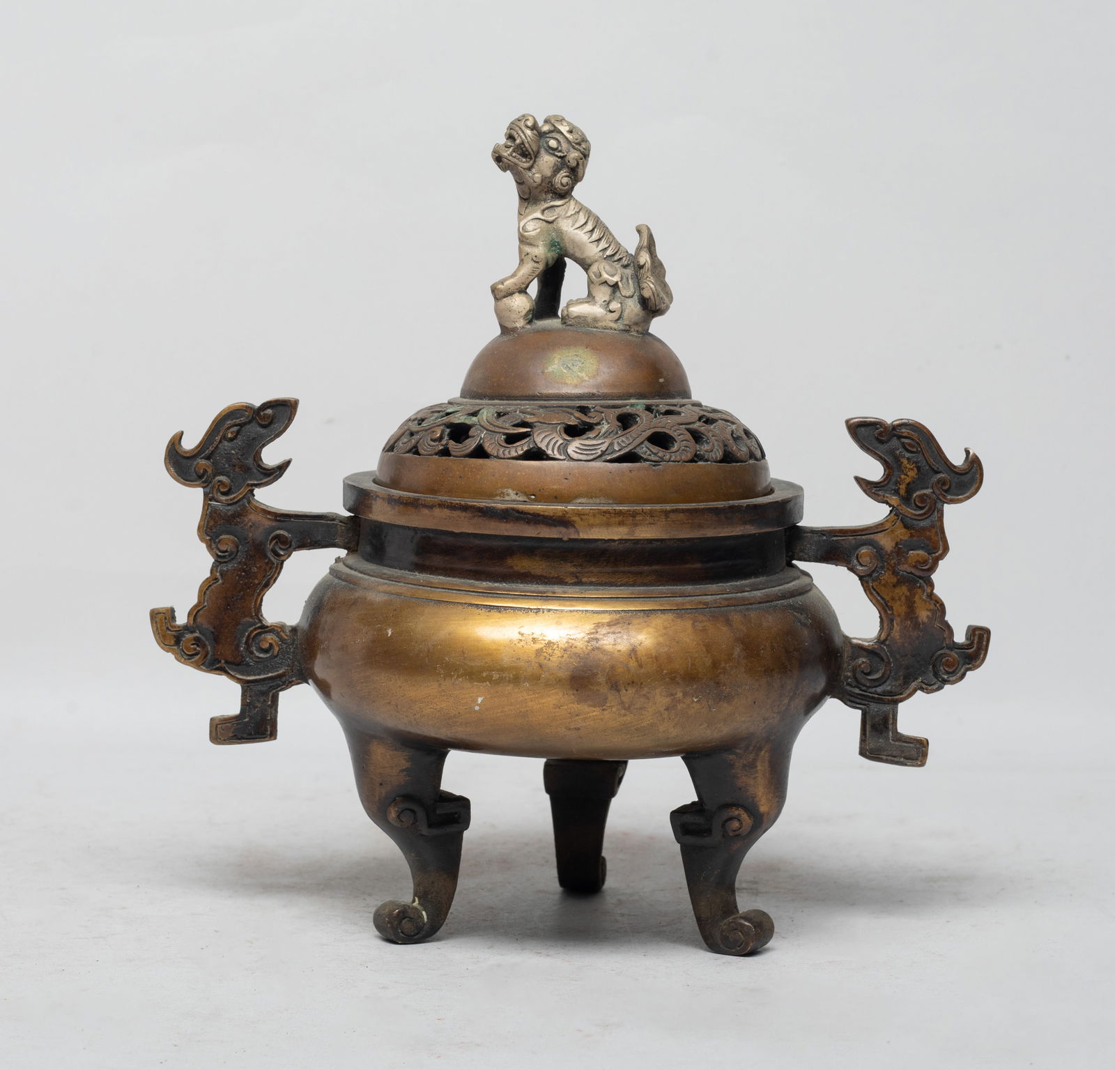 Chinese Export Bronze Covered Censer: Of compressed form resting on three legs, flanked by two flat beast handles, the bottom inscribed with a two-character mark, the cover carved in openwork with twisted dragons and surmounted with a foo