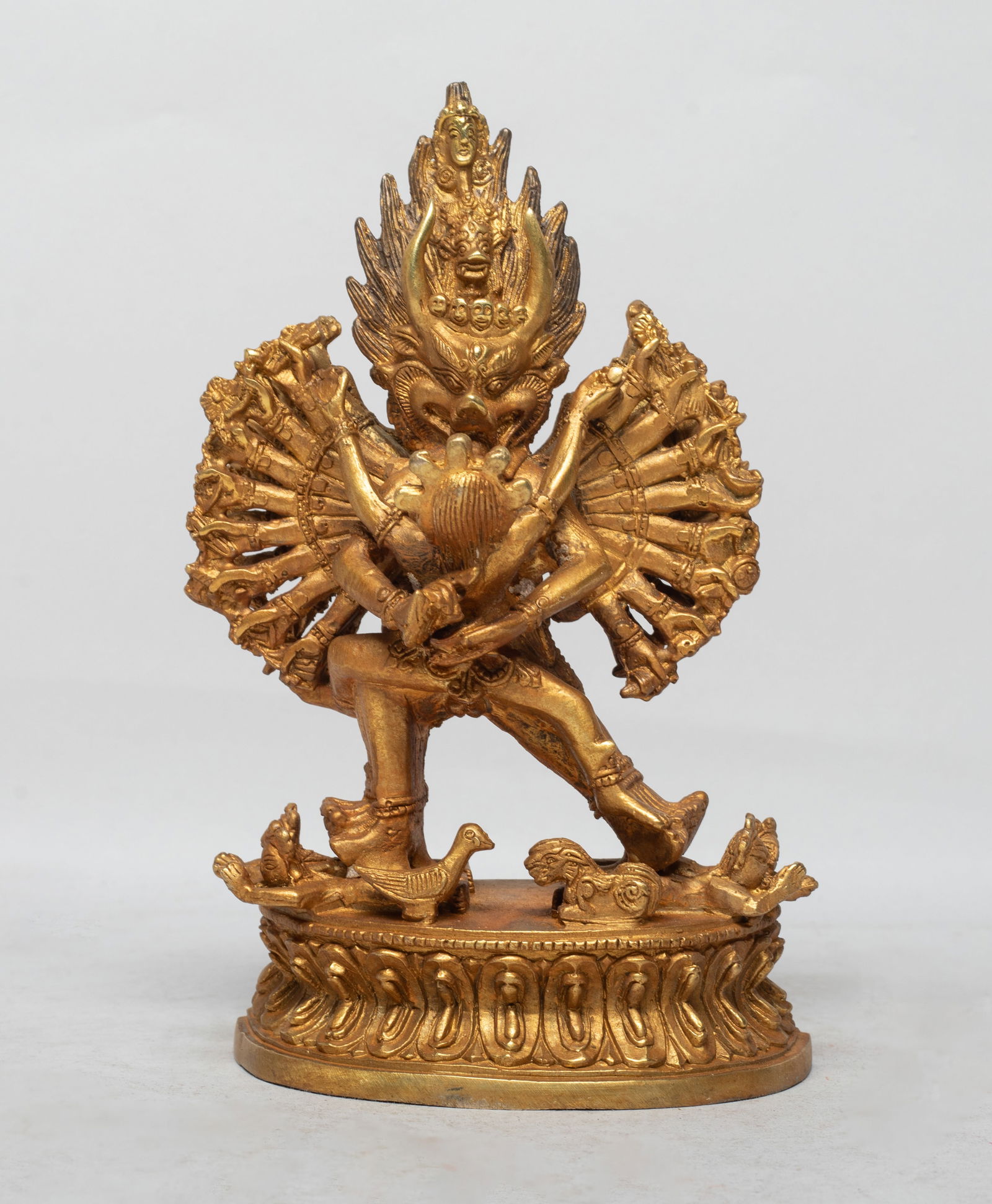 Estate Chinese Gilt Bronze Sculpture of Buddha: The Buddha cast standing on a waisted lotus base, with multiple pairs of legs stepping on attendants and multiple pairs of hands holding various implements, the front pair of arms holding an attendant