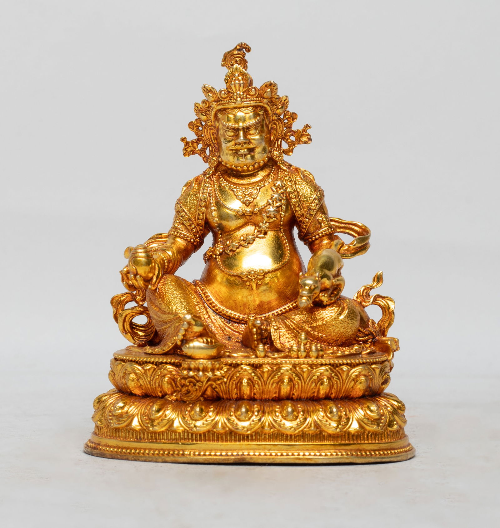 Chinese Gilt Bronze Sculpture of Buddha: The Buddha cast seated on a double layered lotus base, the left hand holding a mouse and right hand holding a conch shell, wearing delicate diadema and jewelry, the bottom inscribed with four