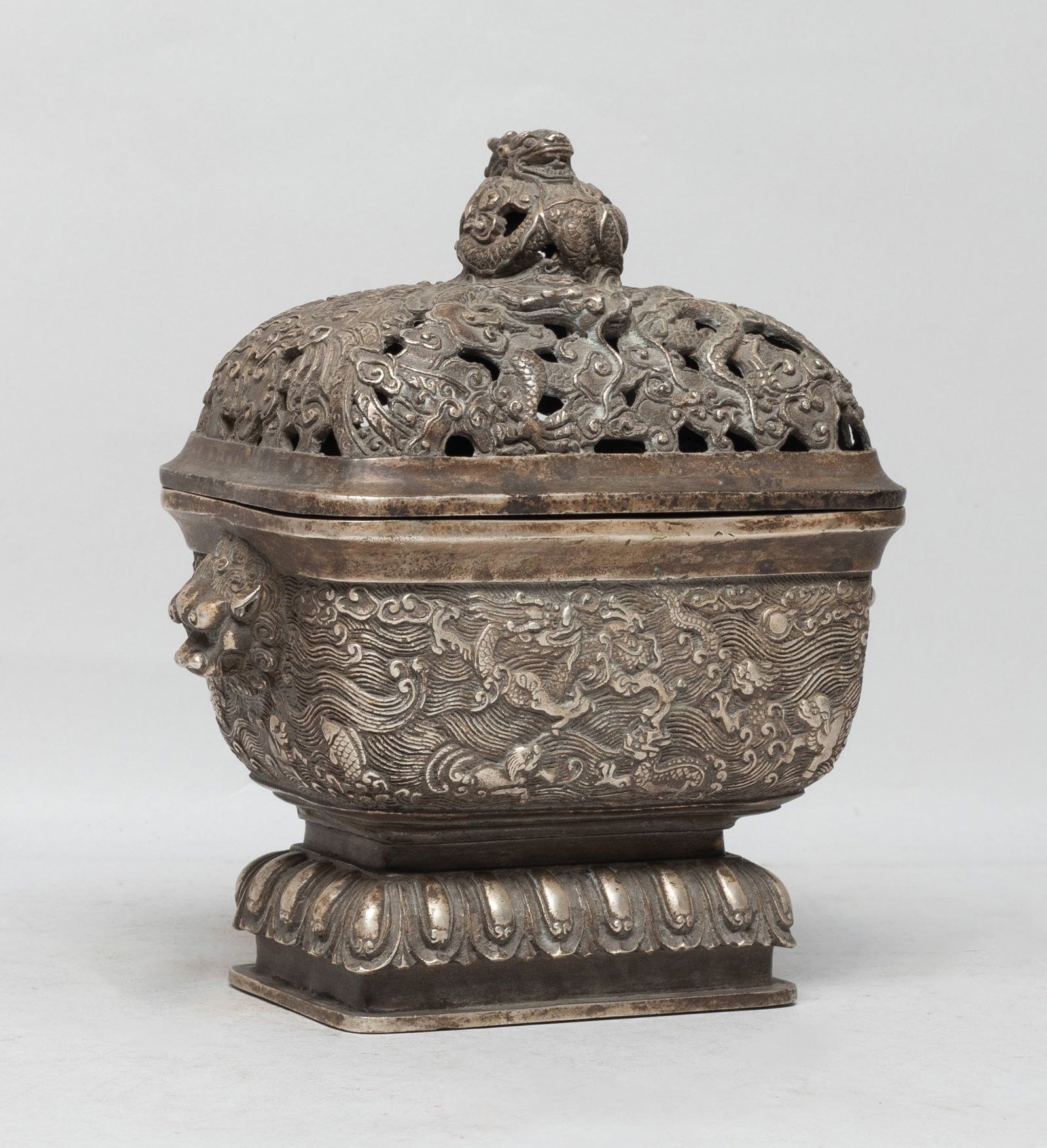 Estate Chinese Bronze Covered Censer: Of rectangular section, the censer exterior cast with dragons, beasts and fish over waves, flanked by two raised beast masks, the foot with a band of lotus petals, the lid carved in openwork with drag