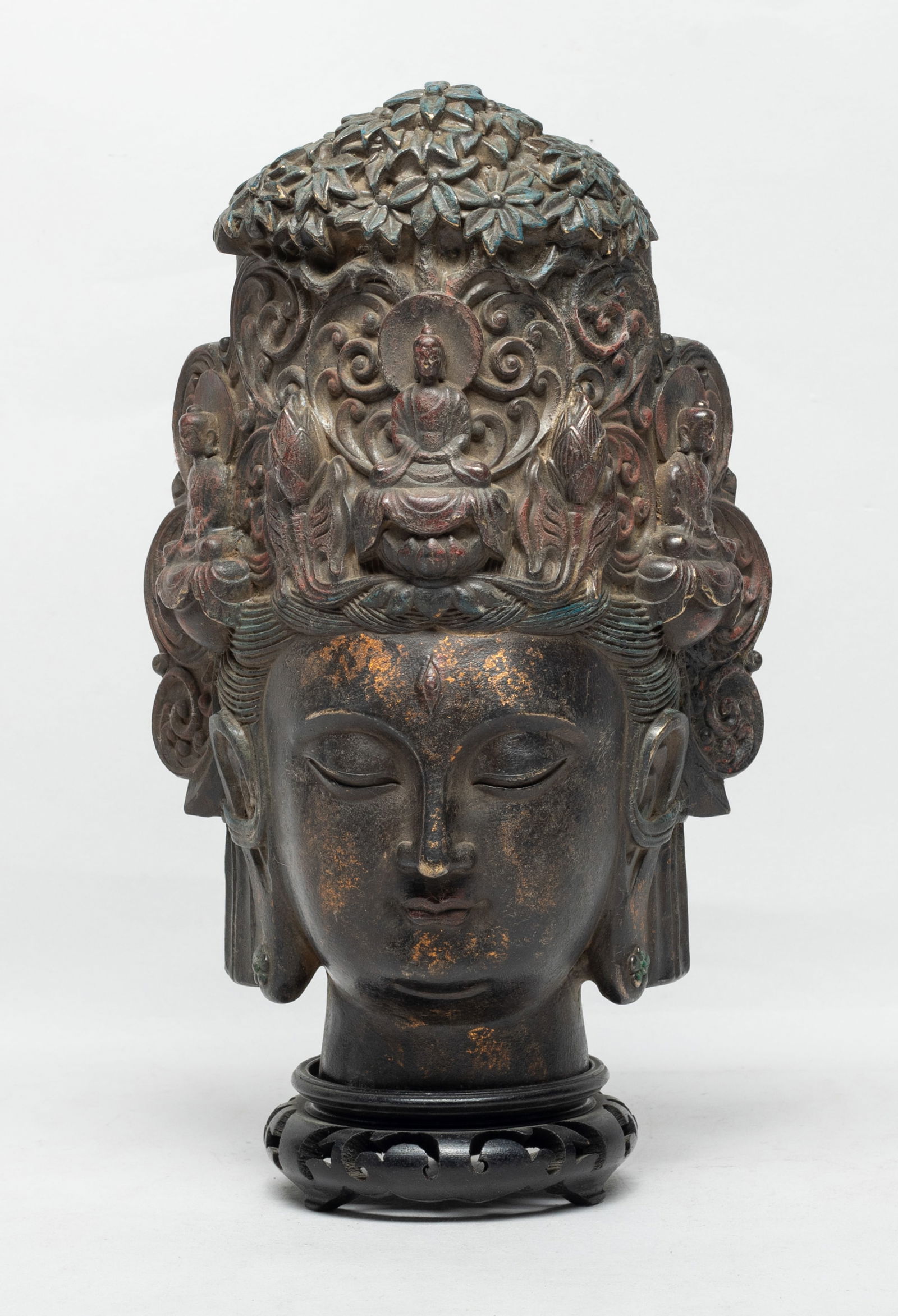 Large Chinese Bronze Buddha Head: The full fleshy face with downcast eyes accentuated by wide arched eyebrows, straight nose, plump pouty lips and subtle double-chin, all between long pendulous ears, beneath neatly-dressed hair drawn