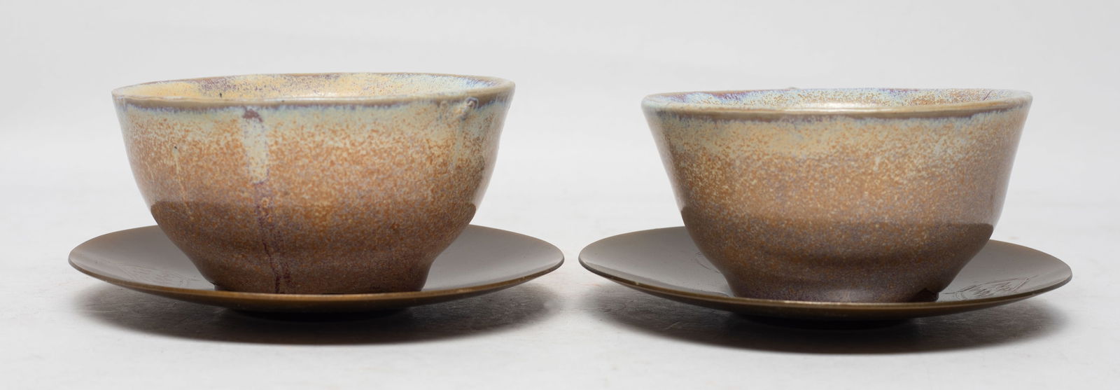 Two Chinese Jun Type Porcelain Tea Cups: Each cup covered with mottled brown, purple and milky blue glaze, with metal saucers. Approx. 3.6*1.9 inch (each cup size). The Estate of the Store Closed Sale, Little Tokyo. Los Angeles. 2025.