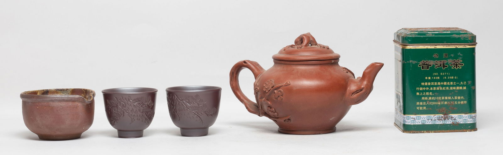 Vintage Chinese Zisha Tea Pot, Tea, Cups: Including a zisha tea pot carved with plum blossoms, the bottom with a mark, a bowl, two tea cups, and a jar of tea. Approx. 7.5*4.6*4.5 inch (tea pot size).
