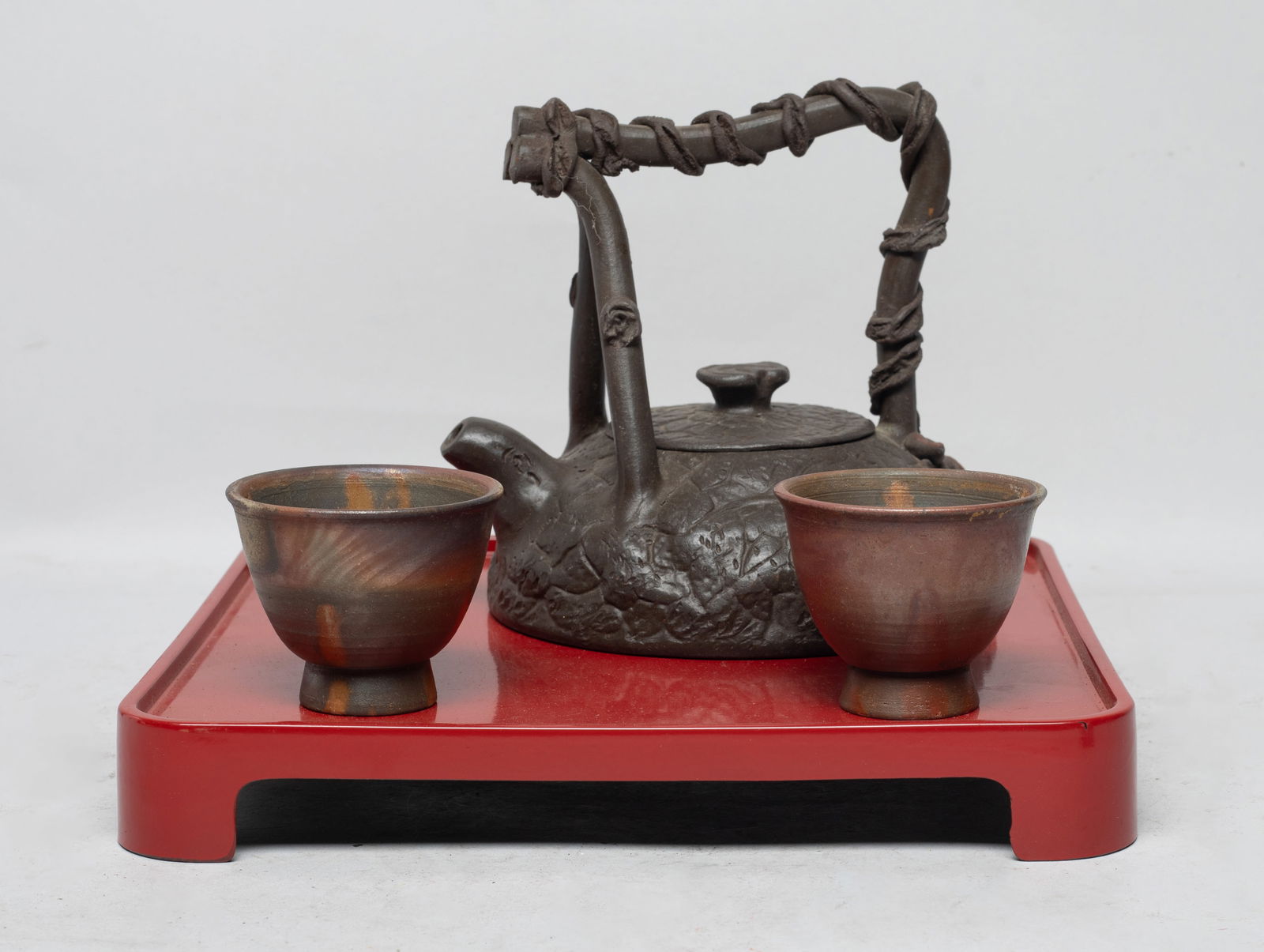 Vintage Chinese Yixing Zisha Tea Pot, Cups: Including two tea cups and a zisha tea pot, the crackled body carved with leaves, the handle wrapped with rope, the bottom with a two-character mark, with a tray. Approx. 5.2*5.6*5.2 inch. The Estate