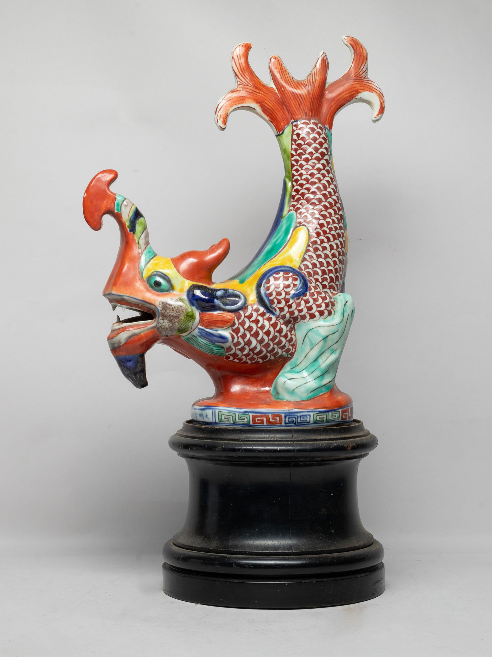 Large Chinese Porcelain Sculpture on Base: Large Chinese porcelain sculpture of mythical beast form, the scaly fish-like body raising up, , applied with red, green, yellow, blue and brown glaze, with a tall wood base. Approx. 14.5*11*5 inch (w