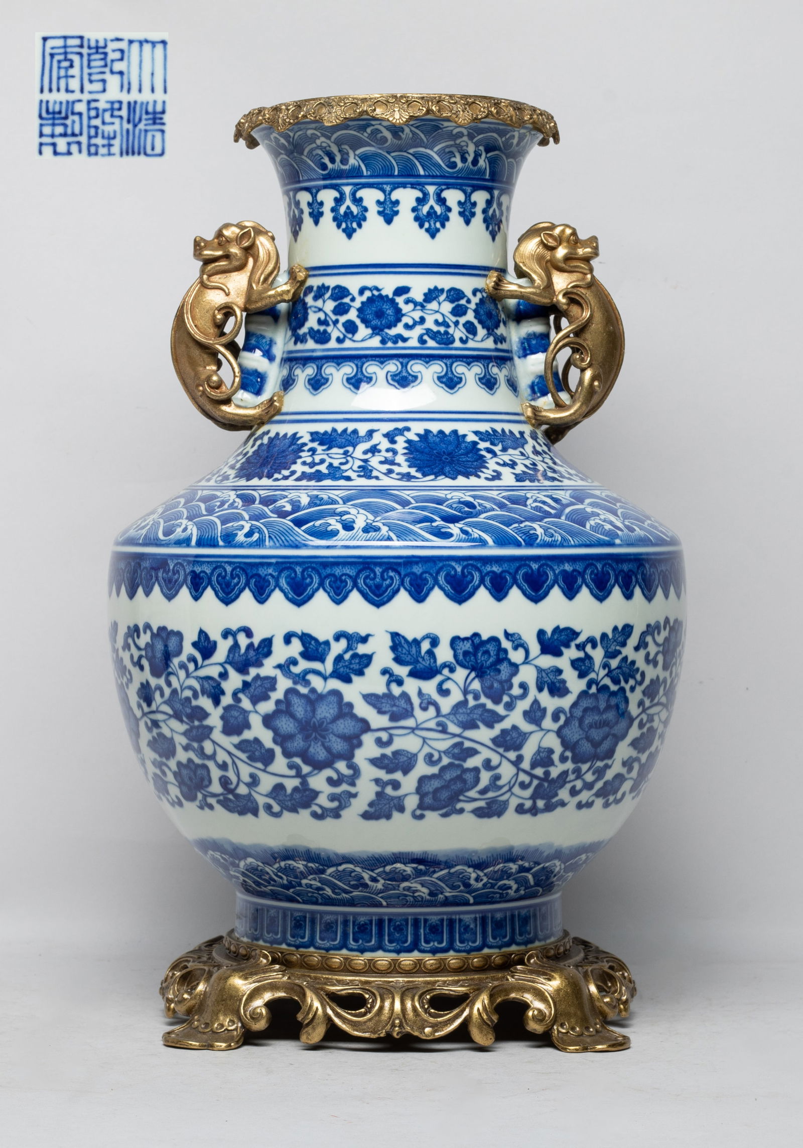 Large Chinese Export Porcelain Vase: The ovoid body rising from a short foot to a gently waisted neck, painted with bands of foaming waves, lotus foliage, ruyi heads and petals, the bottom with a six-character mark, set with metal cast r