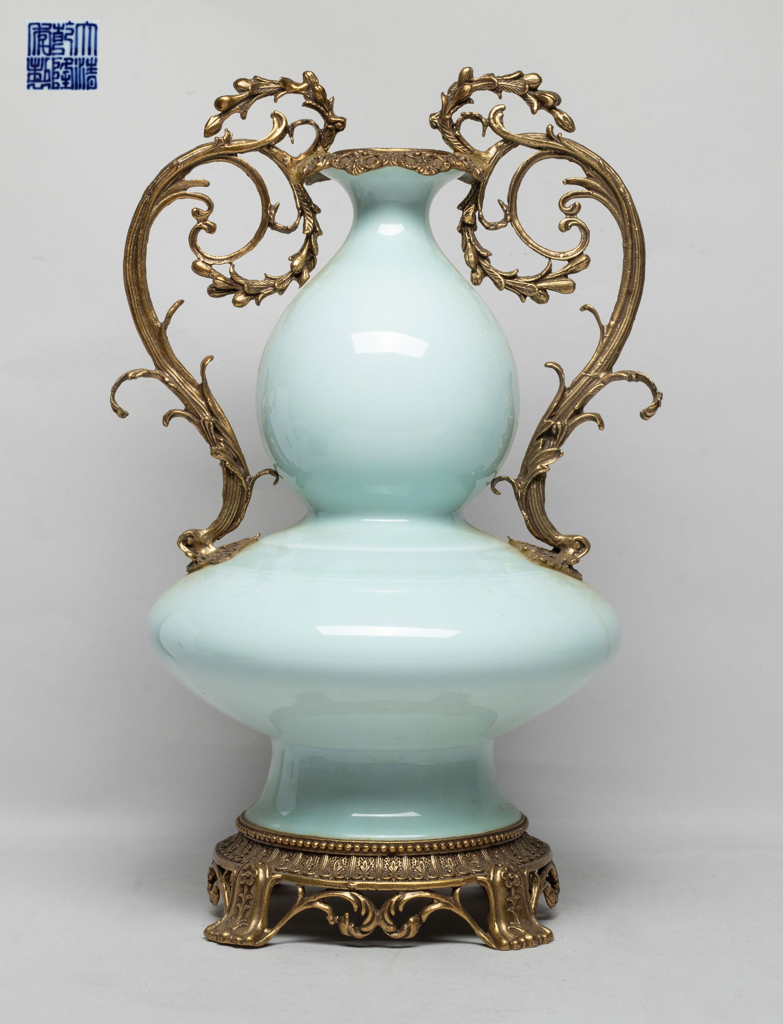Tall Chinese Bean Green Glazed Porcelain Vase: Of double gourd form with a splayed foot, set with metal cast rim, base, and a pair of foliage form handles, the exterior covered with even bean green glaze, the bottom with a six-character mark. Appr
