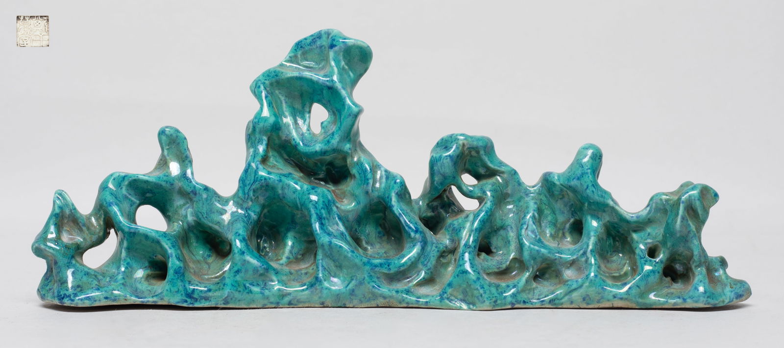 Chinese Flambe Glazed Porcelain Brush Stand: Of horizontal orientation, molded in the shape of a mountain range, covered in turquoise glaze suffused with dark blue streaks, the bottom inscribed with a four-character mark. Approx. 7.7*3*1.7 inch.