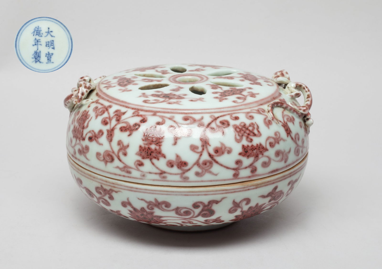 Chinese Copper Red Glazed Porcelain Censer: The censer top pierced with seven apertures and painted with lingzhi, the sides painted with meandering lotus sprays, all in copper-red color, set with two raised chilong forming as handles, the botto