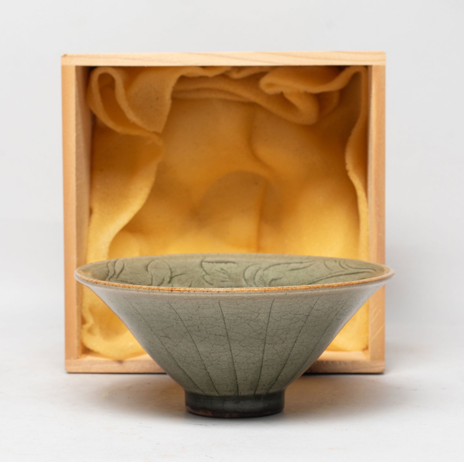 Chinese Yaochou Ware Porcelain Tea Bowl: Of conical shape with a short foot, the interior carved in low relief with large blooms and leafy stems, covered overall with crackled olive green glaze, with a lidless box. Approx. 5.25*2.25 inch (w/