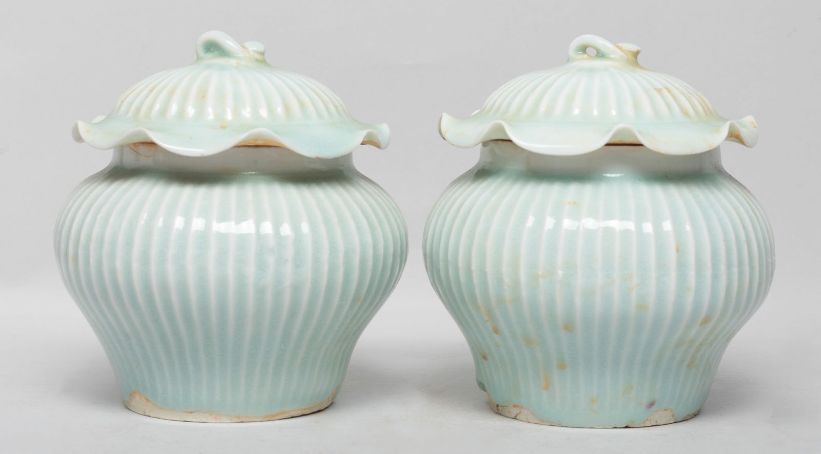 Two Chinese Hutian Porcelain Jars: Of tapered ovoid form, the lid with undulating rim, the body and lid exterior carved with raised vertical borders, covered with pale sea green glaze. Approx. 4.6*4.5 inch (each). The Estate of the Con