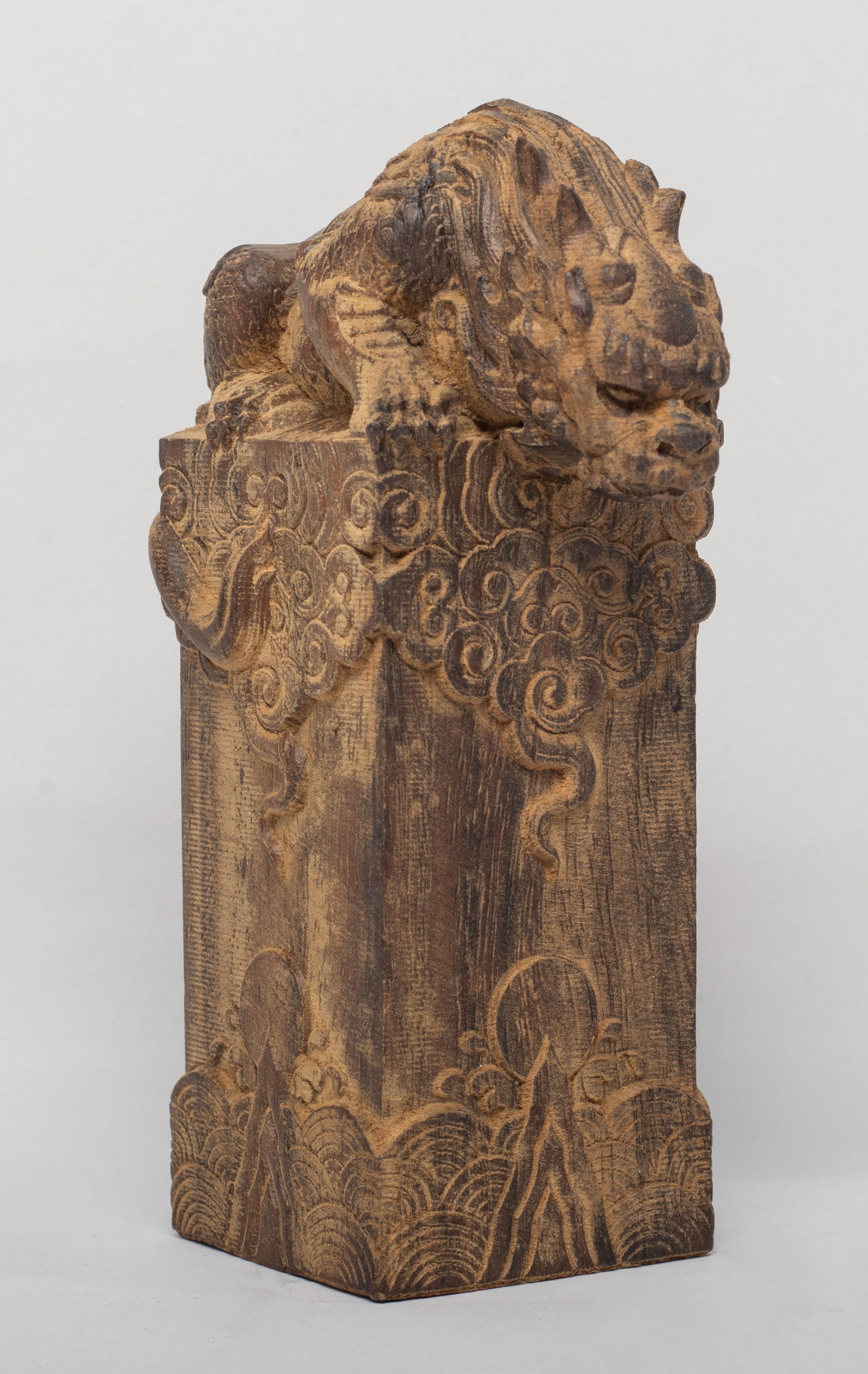 Chinese/ South Asian Agarwood Sculpture: Of tall square section, each side carved with scrolling clouds above a sun raising out of foaming waves, the top carved with a crouching beast with a scaly body and a curled tail. Approx. 307 gram, 5.