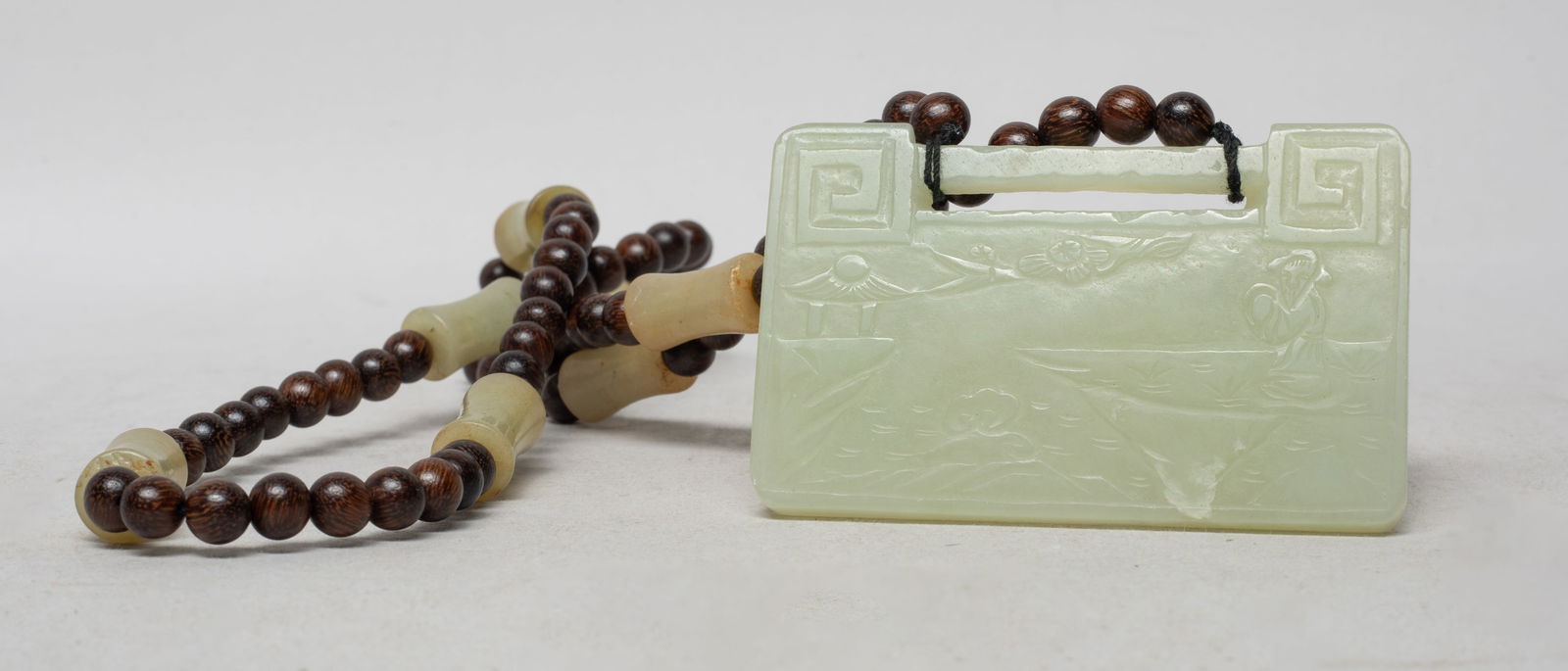 Chinese Agarwood Necklace, Jade Pendant: Long Chinese agarwood and russet jade bead necklace, suspended with a rectangular shaped pale celadon jade plaque, one side carved with a figure standing at riverbank, with lingzhi and distant pavilio