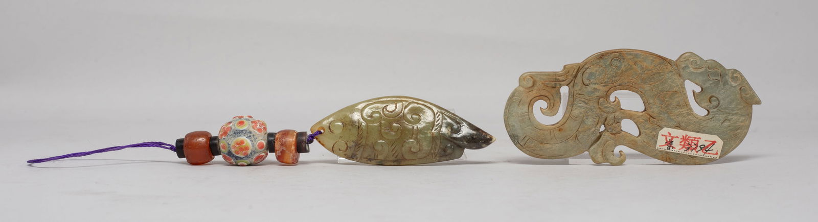 Estate Two Chinese Export Jade Pendants: One jade pendant carved of S-shaped dragon form, the other carved of archaistic fish form, the body incised with scrolls, with two agate beads and a glass bead. Approx. 3.8*1.67 inch (larger jade size