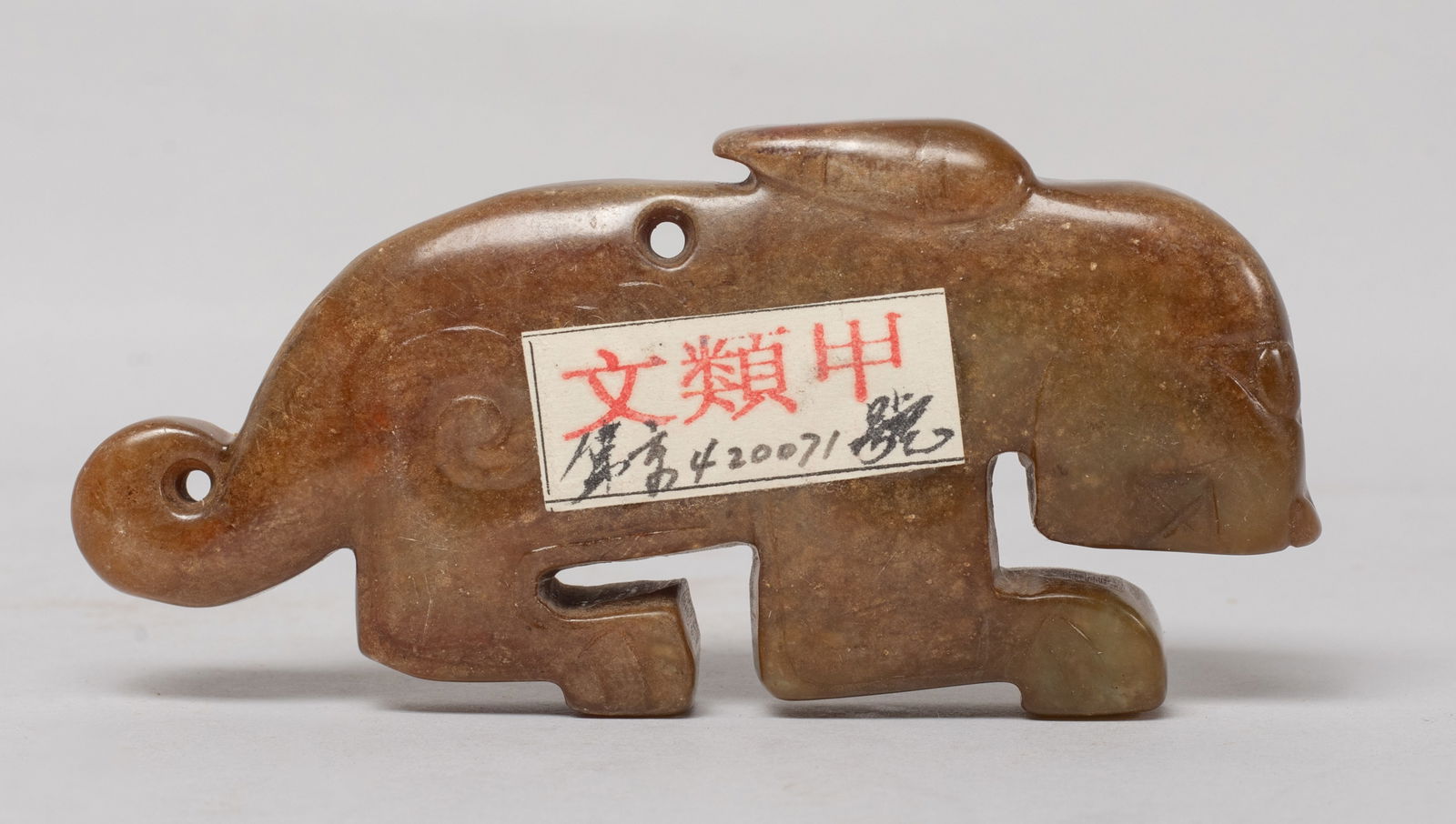 Chinese Export Russet Jade Pendant: The flat pendant worked of stylized beast form, drilled at the back centre for suspension. Approx. 3.4*1.65*0.5 inch. The Estate of the Store Closed Sale, DTLA. 2021