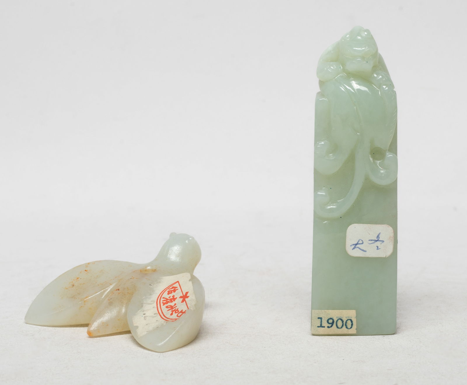 Two Chinese Export Jade Carved Toggles: Including a pale celadon jade toggle of tall rectangular shape, carved on the top with a seated beast, and a russet jade toggle carved as a bird with winds stretched out. Approx. 3.3*3.3*0.7 inch (lar