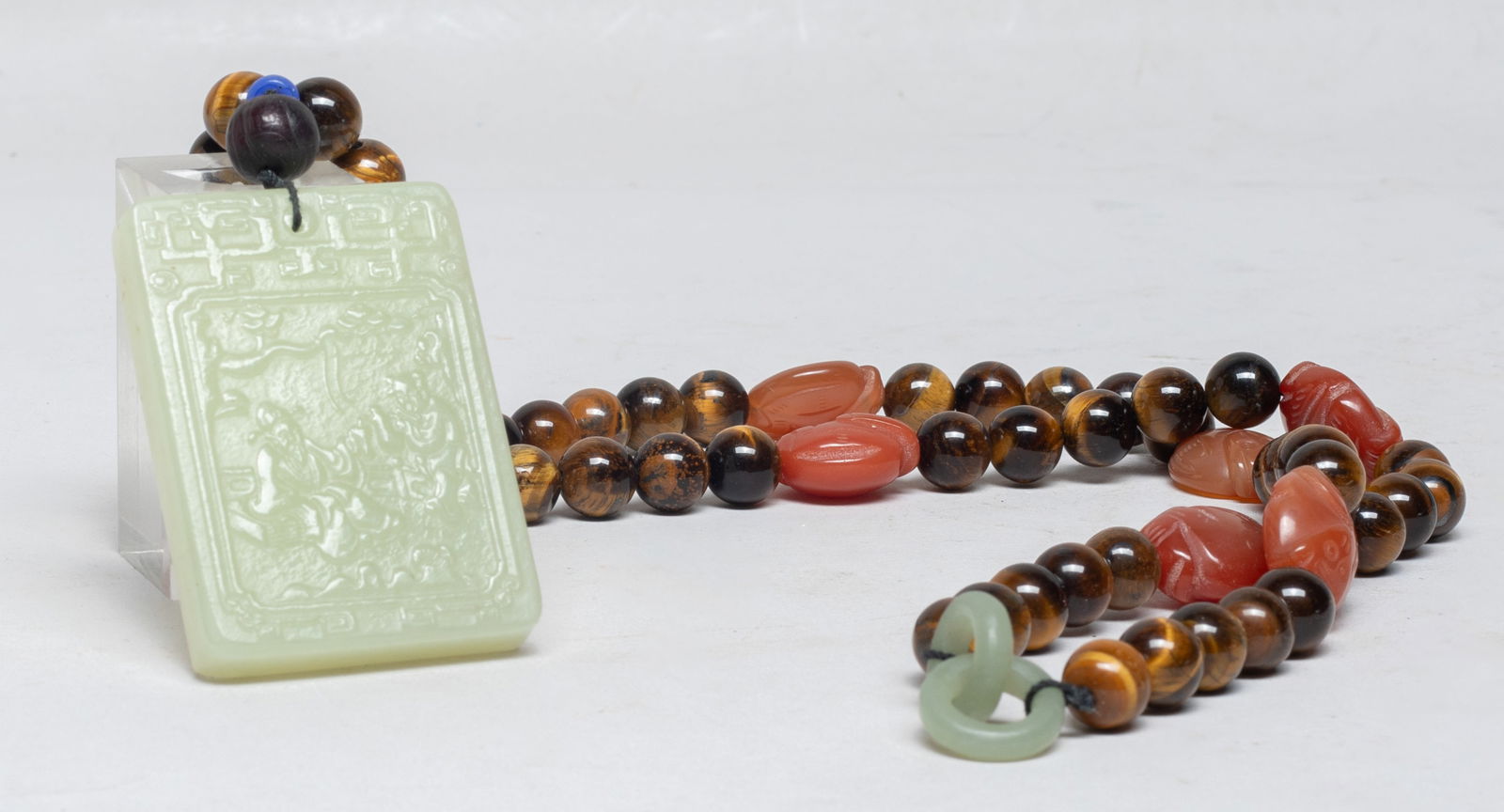 Vintage Chinese Gemstone Necklace w/ Jade Pendant: Chinese tiger eye gemstone bead and monkey form agate bead necklace, with a jade plaque, one side carved with a scholar and a boy under a pine tree, the reverse inscribed with related passages. Approx