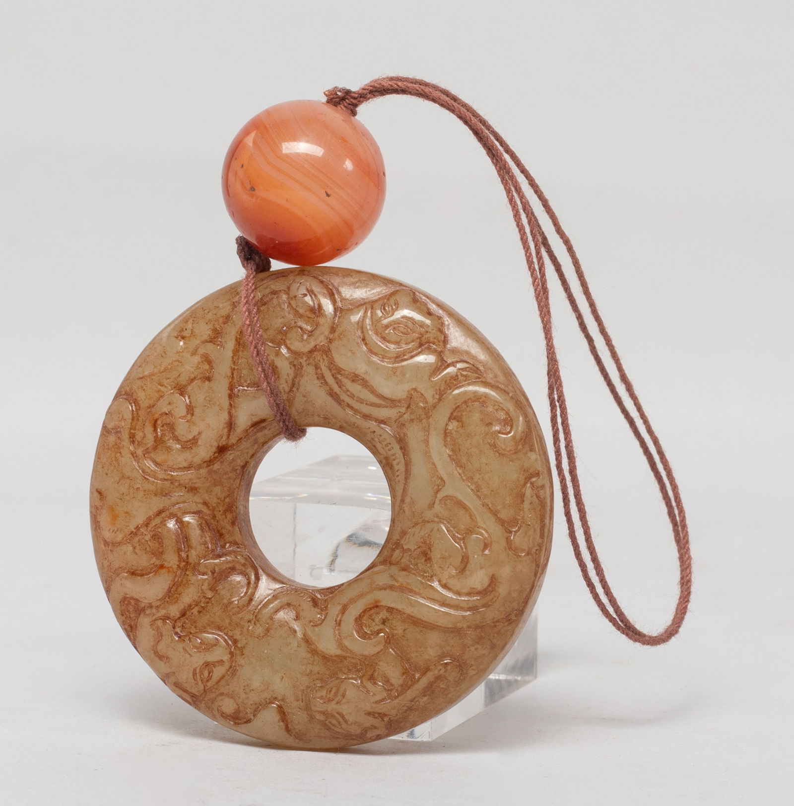 Chinese Russet Jade Pendant w/ Agate Bead: Chinese russet jade huan shaped pendant, either side carved with sinuous chi dragons, with an agate bead. Approx. 2 inch D (jade size). The Estate of the Store Closed Sale, DTLA. 2021