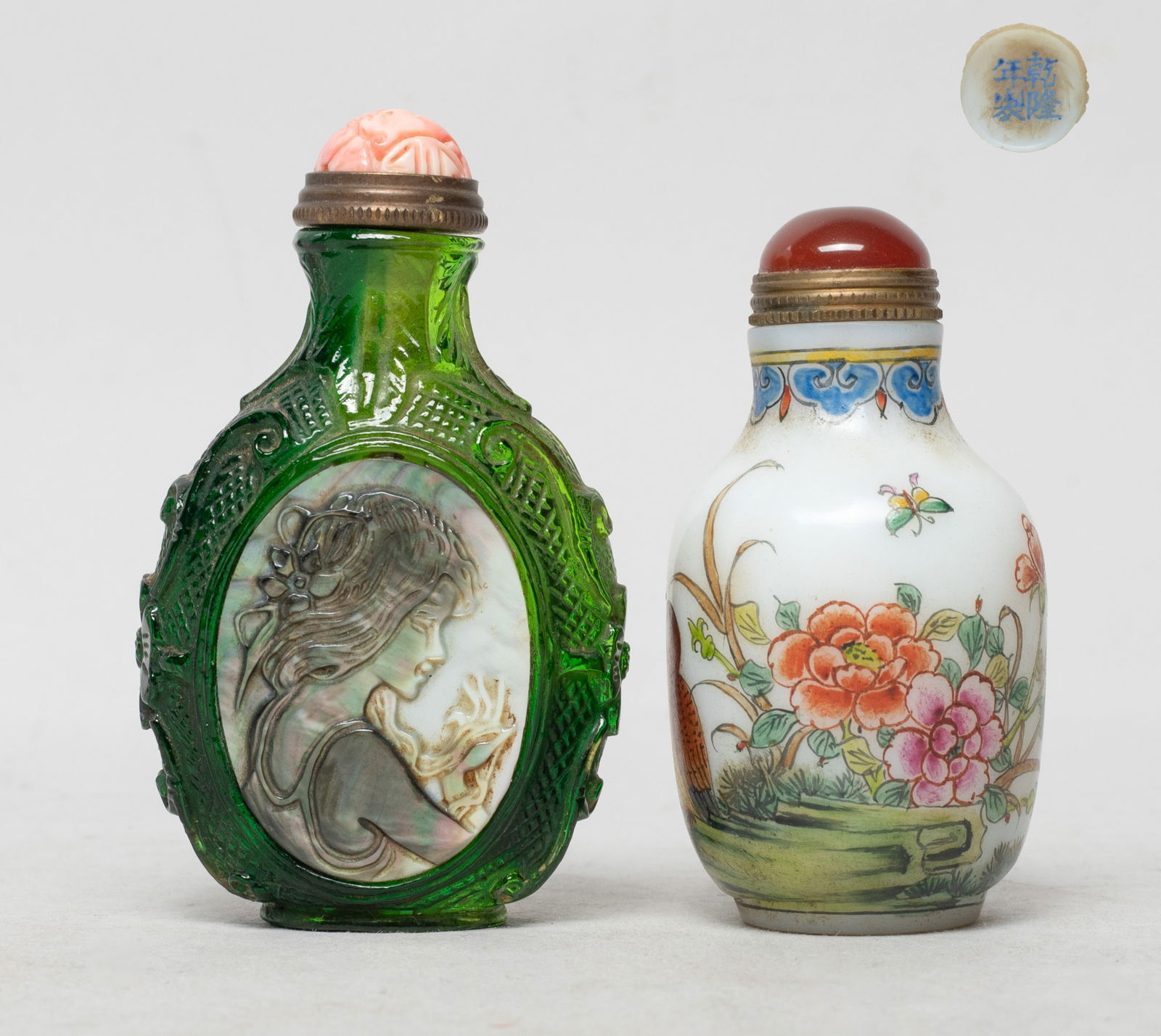 Two Chinese Peiking Glass Snuff Bottles: One snuff bottle of ovoid form, the exterior painted with birds, flowers and a butterfly against opaque white glass body, the other green glass snuff bottle carved with flowers, either side inlaid wit