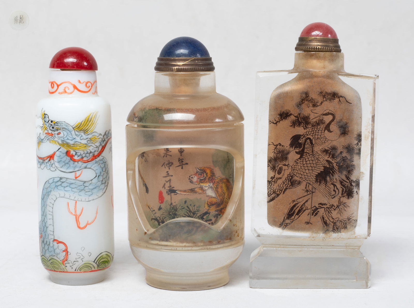 Three Chinese Peiking Glass Snuff Bottles: One snuff bottle painted with a five-clawed dragon above waves, the bottom marked two characters, one painted on inside with cranes and pine trees, the other inside painted with two monkeys among bran