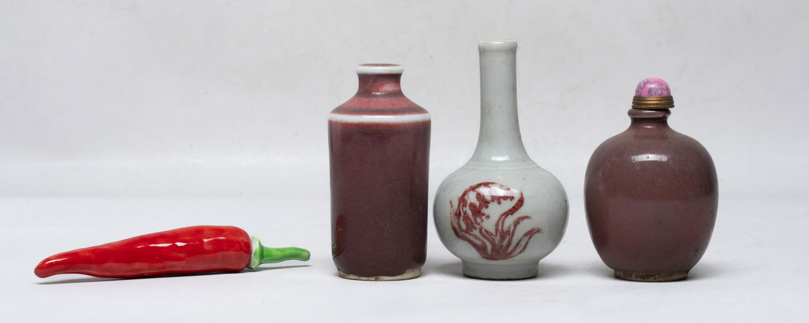 Estate Set Chinese Porcelain Snuff Bottles: Set of four porcelain snuff bottles: one of pepper form; one of cylindrical shape, the exterior covered in dark red glaze; one of ovoid form, the exterior covered in brown glaze; the other of globular