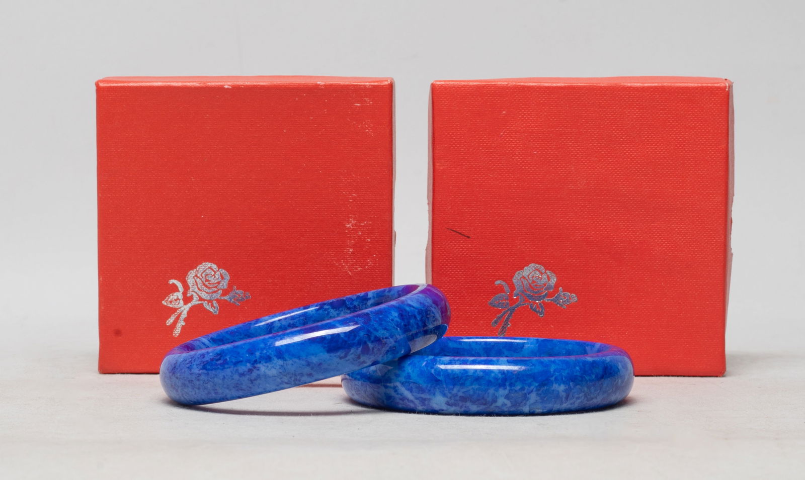 Two Chinese/ Asian Colored Stone Bangles: Two Chinese / Asian colored stone carved bangles, with boxes. Approx. 3.2 inch outer diameter, 2.5 inch inner diameter (each).