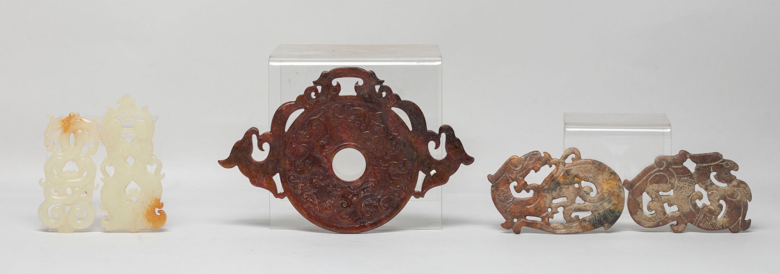 Set Chinese Export Stone Carved Pendants: Set of five Chinese stone carved pendants: one carved as a pair of dancing figures; one as a pair of intertwined dragons; one as a disc flanked by two dragons; the other two carved of S-shaped archaic
