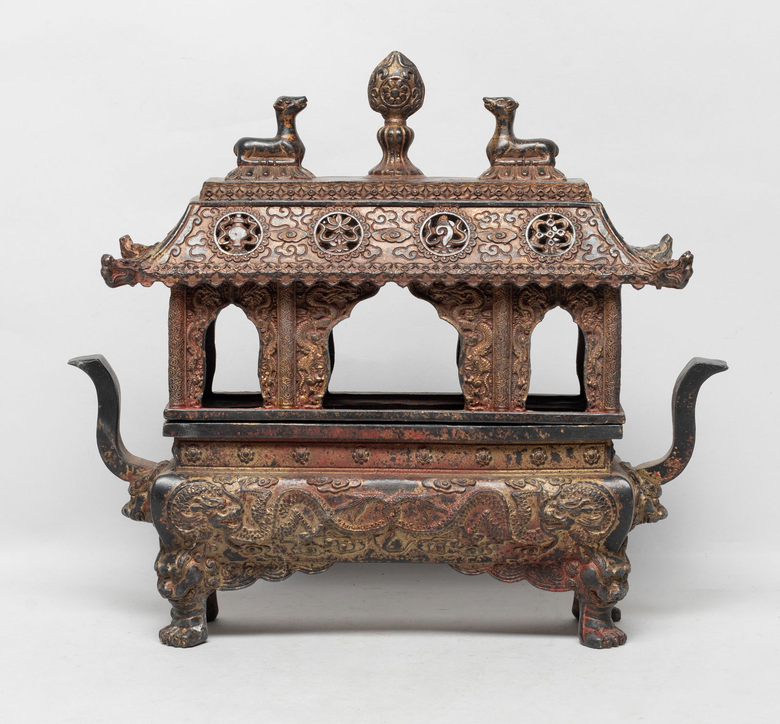 Estate Chinese Tibetan Bronze Cabinet Censer: The censer body of rectangular section, flanked by two handles, cast with sinuous dragons amidst clouds, supported on four mask-to-paw legs, the pavilion form cover carved with dragons around the colu