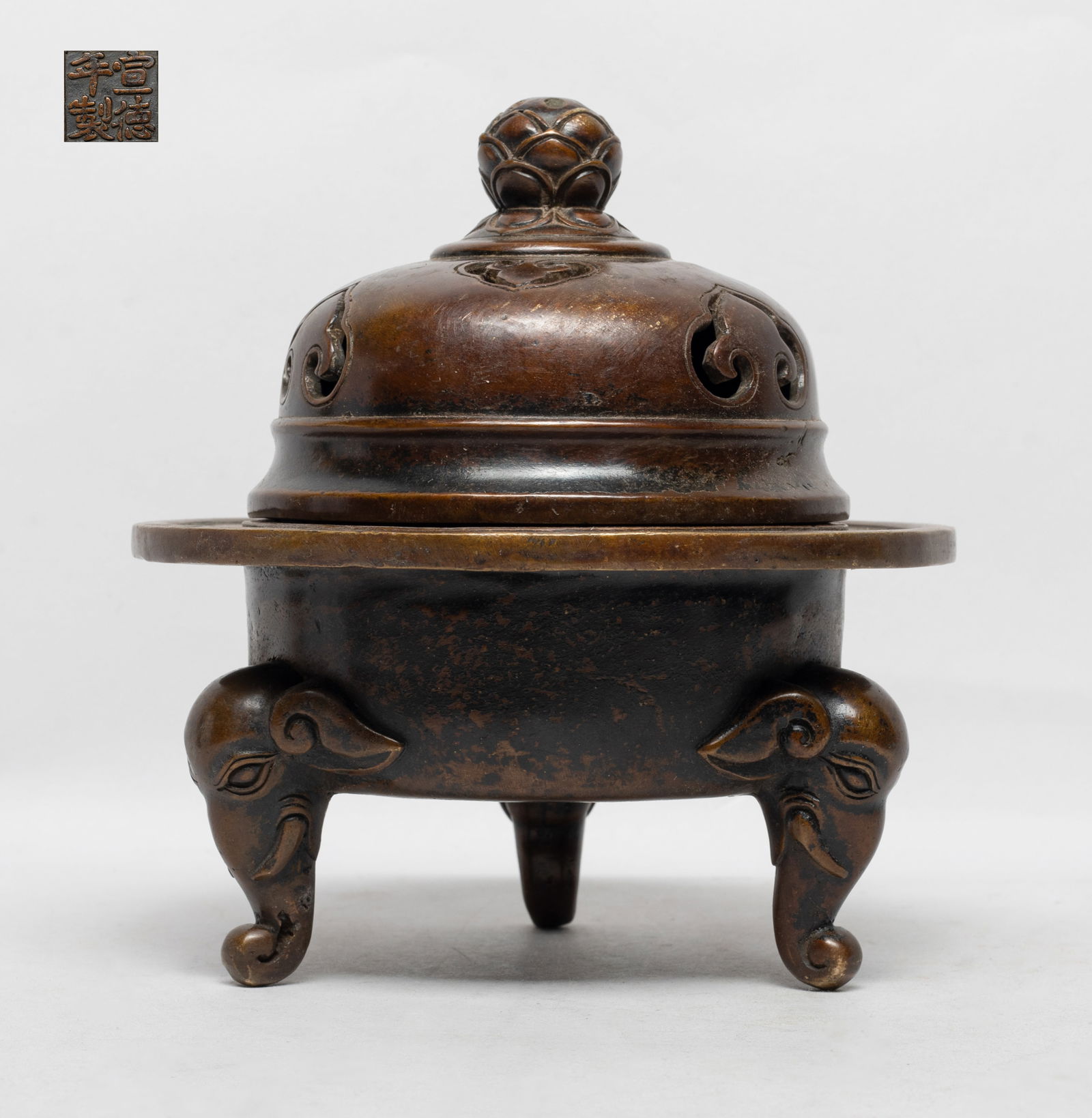 Estate Chinese Bronze Covered Censer: The censer body supported on three elephant head legs, the bottom incised with a four-character mark, the lid carved in openwork with ruyi heads and surmounted with a lotus finial. Approx. 6.6*6.2 inc