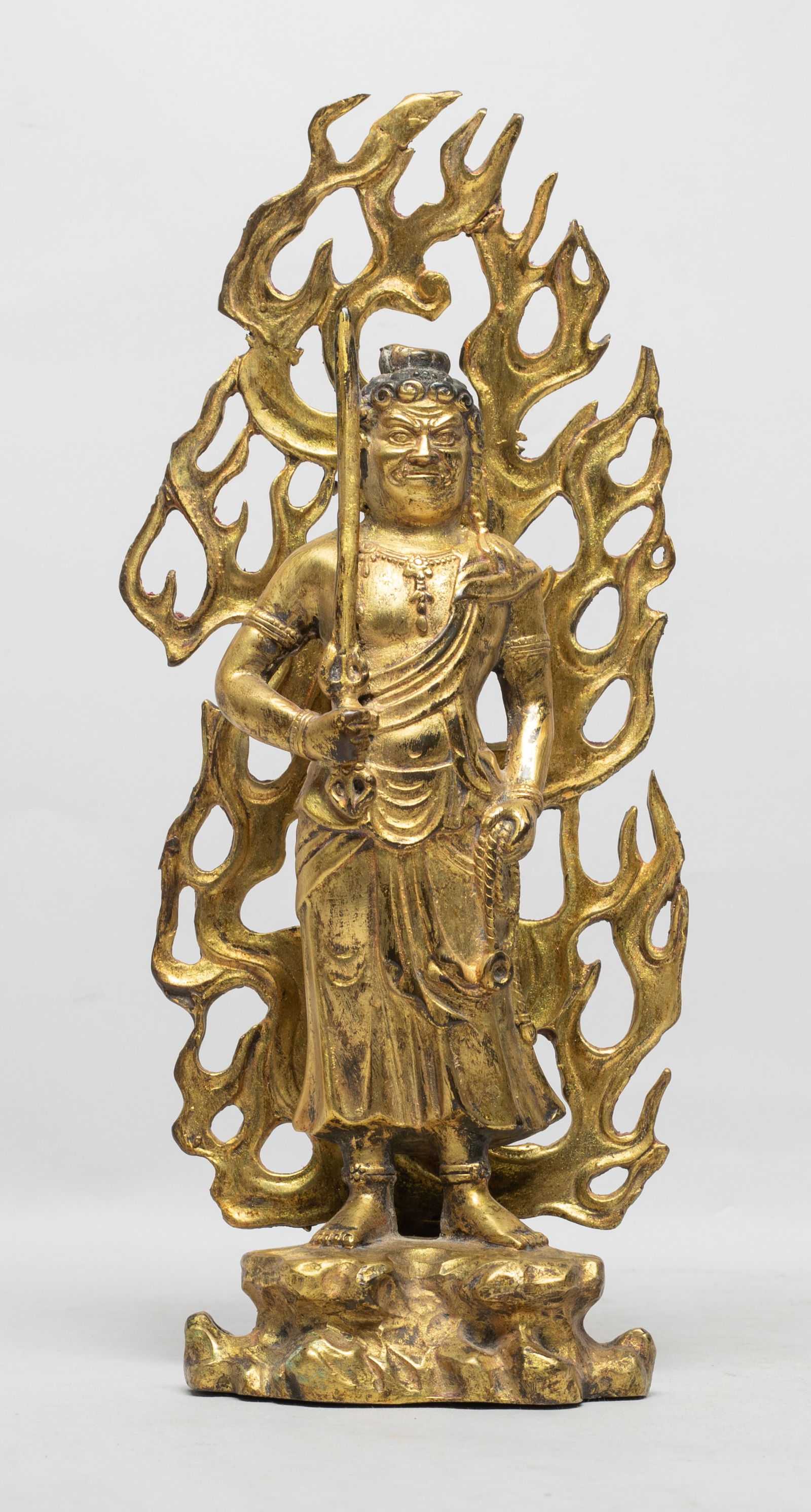 Rare Asian Gilt Bronze Buddha: The Buddha cast standing on rock shaped base, the left hand carrying rope and right hand holding a sword, on his back with flame mandorla. Approx. 11*4.7*2.3 inch.