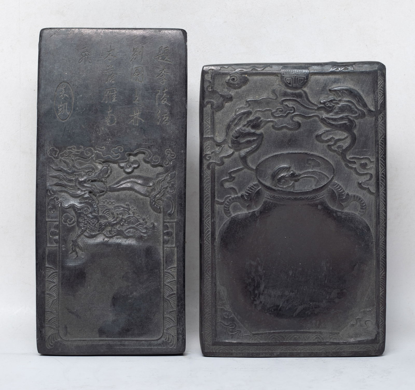 Estate Two Chinese Ink Stones: One ink stone carved with a dragon emerging from waves and spraying clouds, the other carved with a bat in a large vase under two bats among clouds, with inscription on underside. Approx. 8.9*4.1 inch