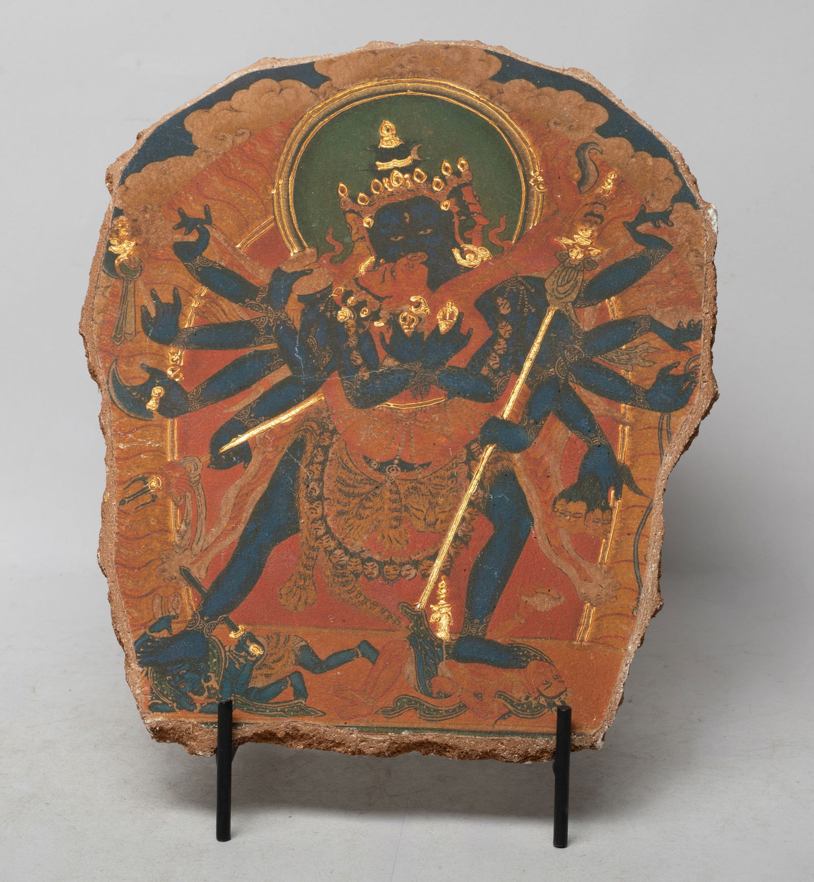 Estate Chinese/ Tibetan Tangka Painted on Clay: Chinese / Tibetan painted on clay tangka, the Buddha stepping on servants and his hands holding various implements, with stand. Approx. 9.7*8 inch (w/o stand).