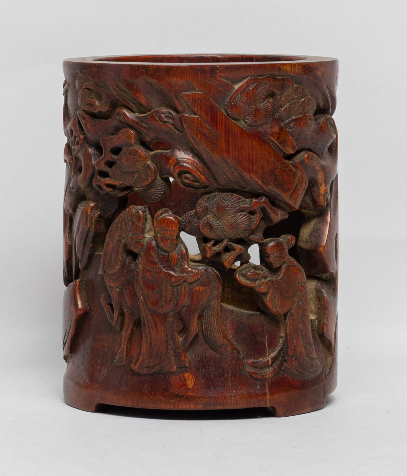 Chinese Carved Bamboo Brush Pot: Of columnar form, carved in openwork with a scholar and a horse under a gnarled pine tree, his servant holding a tray aside, and a deer holding gourd and lingzhi on its back. Approx. 5.1*4 inch.