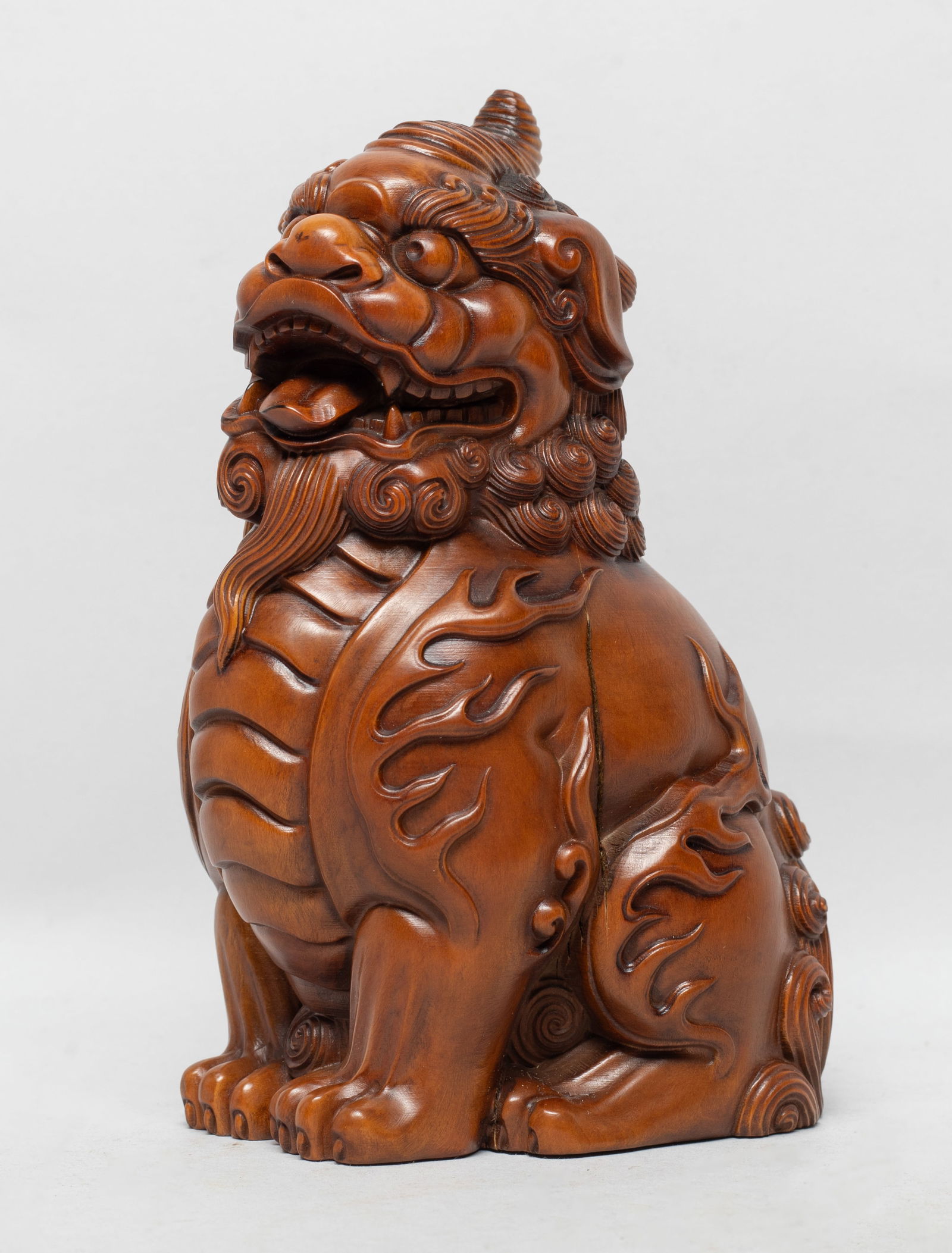 Estate Chinese Wood Sculpture of Foo-dog: Carved as singled-horned mythical beast in crouching pose, detailed with bulging eyes, bushy browns and agape mouth bearing its fang, the body with raised spine, curled tail, and flame motif. Approx.