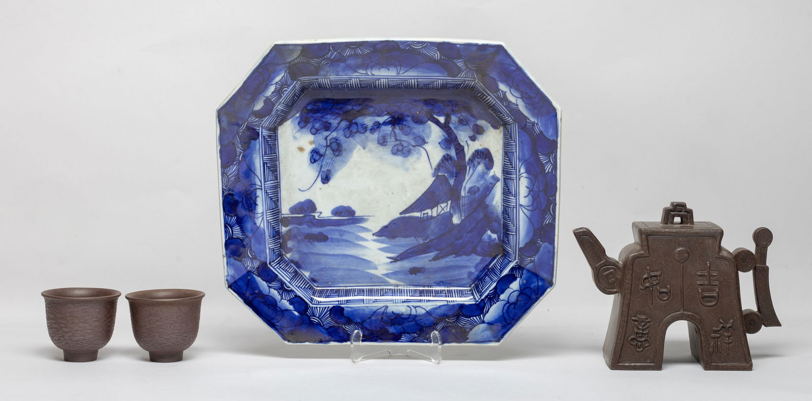 Chinese Export Zisha Tea Pot w/ Drinking Wares: Including a zisha tea pot of special form, either side carved with stylized characters, the lid interior and the pot bottom incised with seal mark, two tea cups, and a blue and white porcelain plate,