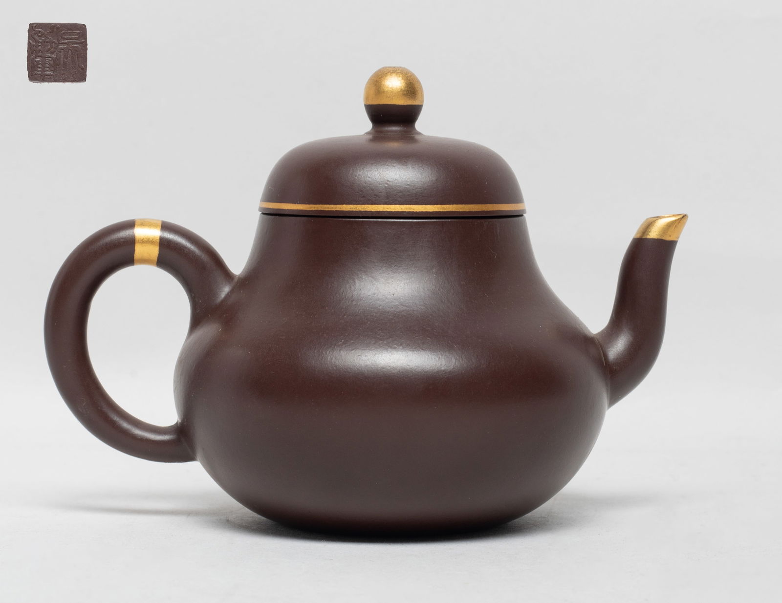 Chinese Gold Painted Zisha Tea Pot: Chinese zisha tea pot, with gold-color painted lid knob and spout mouth, the lid interior with two marks, the bottom with a seal mark. Approx. 5*3.6*3.4 inch.