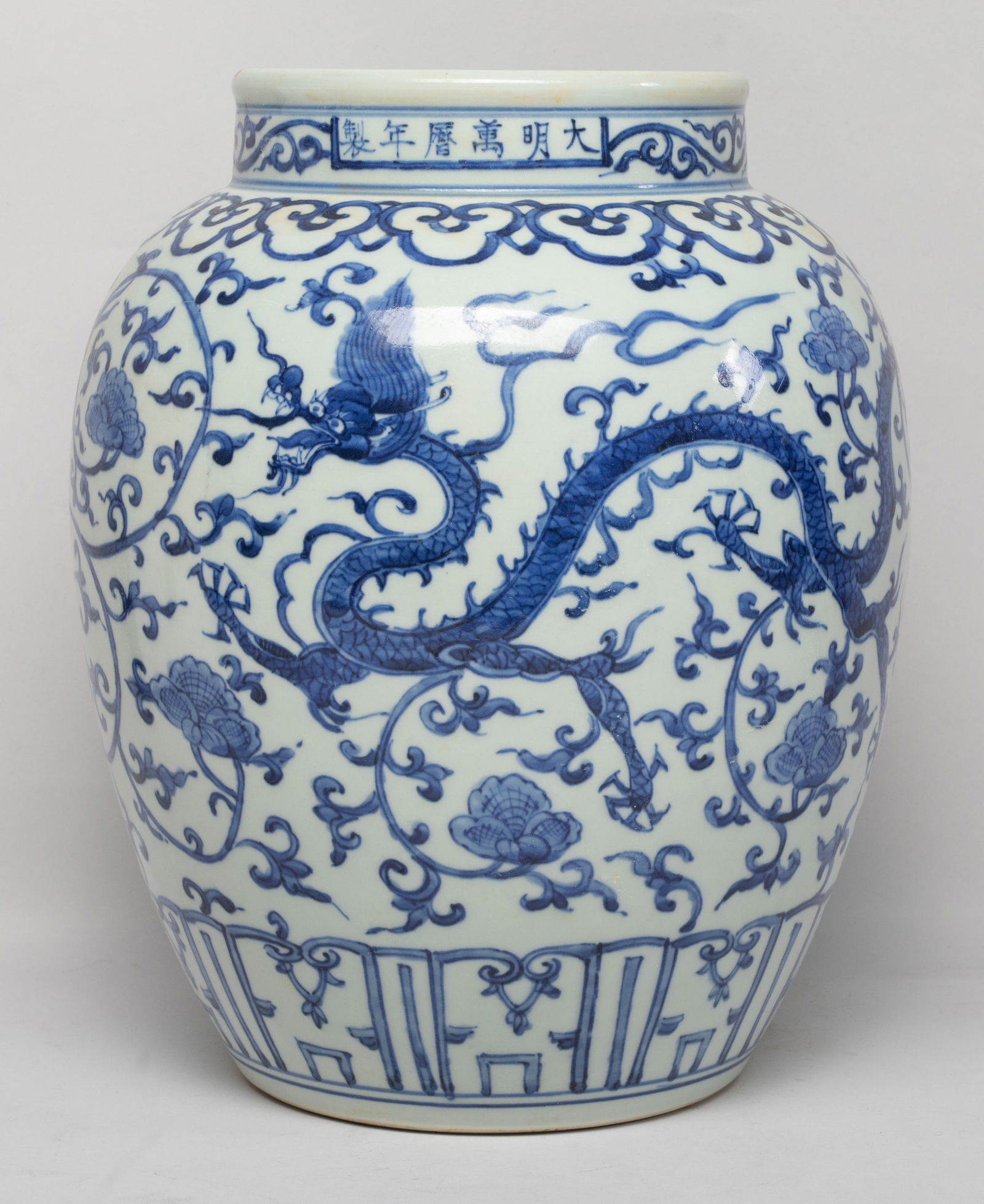 Large Chinese Blue & White Porcelain Jar: Of ovoid form with a short neck, the exterior painted with two five-clawed dragons sinuous amongst undulating foliate scrolls, between bands of ruyi heads and lappets, marked with six characters at th