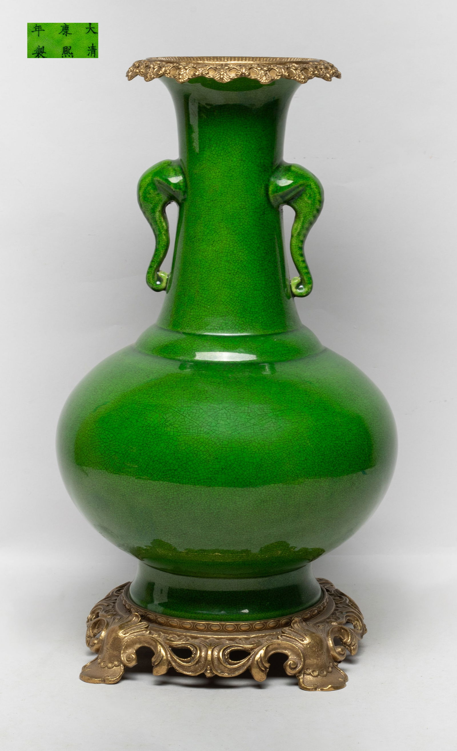 Tall Chinese Turquoise Glazed Porcelain Vase: The compressed globular body rising from a splayed foot to a cylindrical neck and a flared rim, flanked by two elephant head handles, the exterior and interior neck covered with crackled apple green g