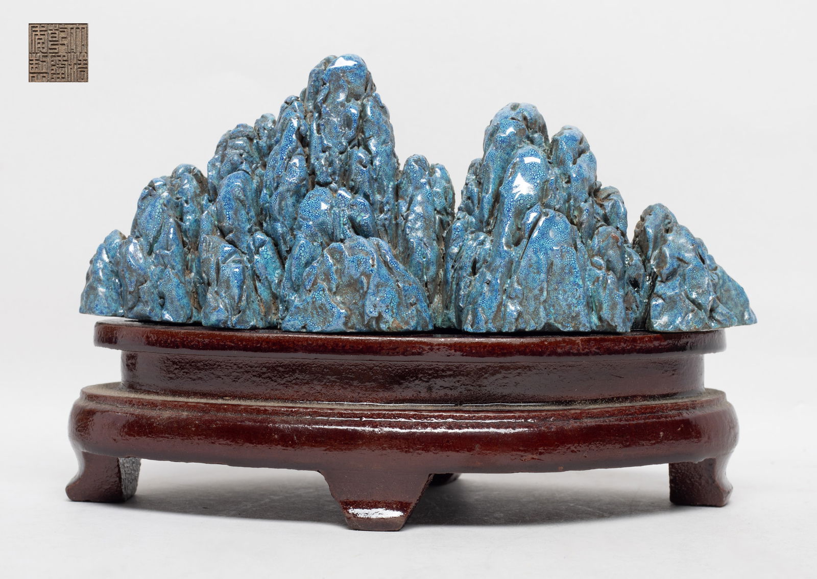 Chinese Flambe Glazed Porcelain Sculpture: Of horizontal orientation, worked in the shape of a mountain range, the exterior covered in turquoise glaze suffused with blue bubble motif, the bottom incised with a six-character mark, with stand. A