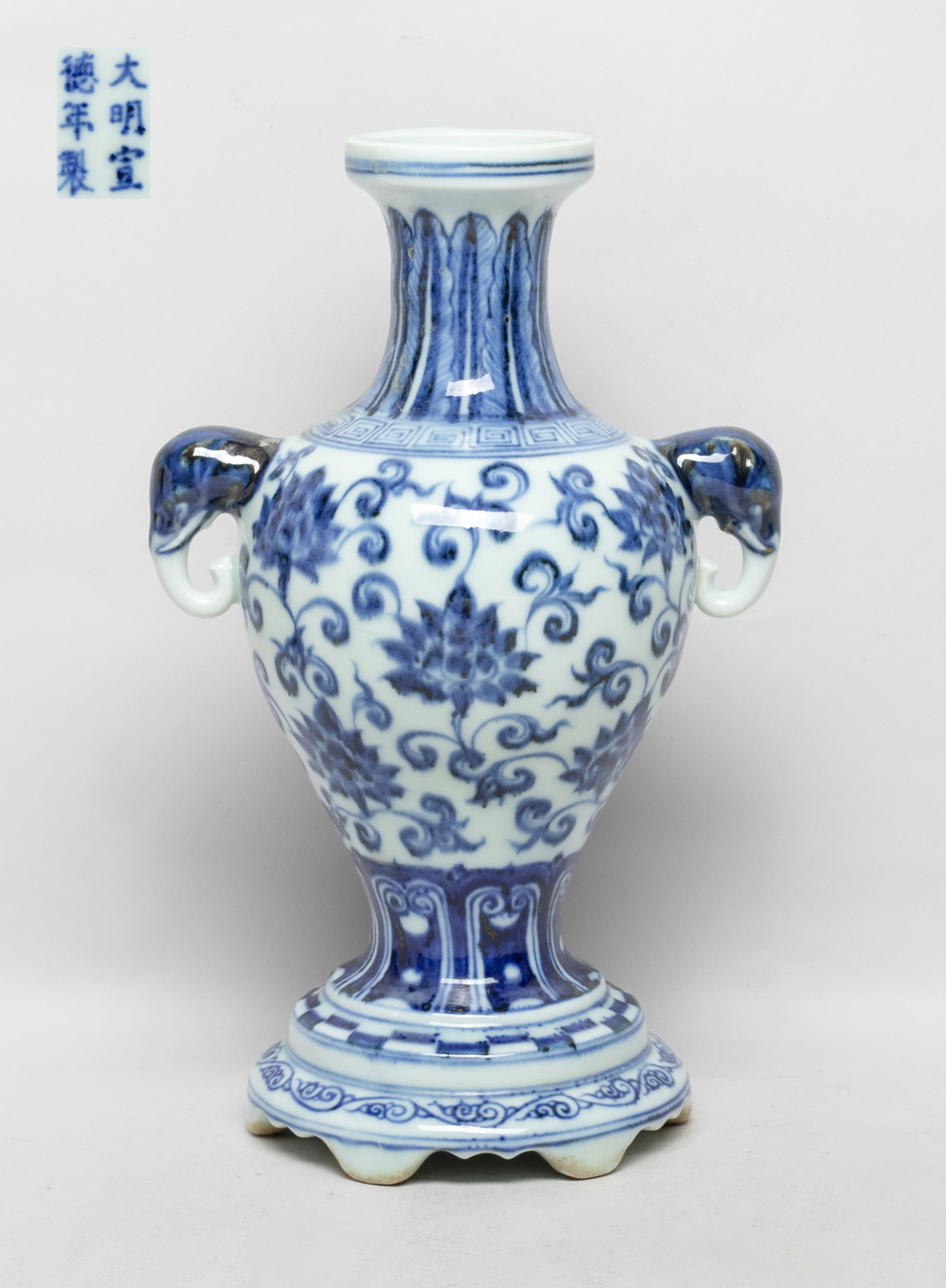 Chinese Export Blue & White Porcelain Vase: Of tapered ovoid shape rising from a splayed foot to a waisted neck and dished rim, flanked by two elephant head handles, painted with lotus foliage between bands of overlapping leaves and lappets, th