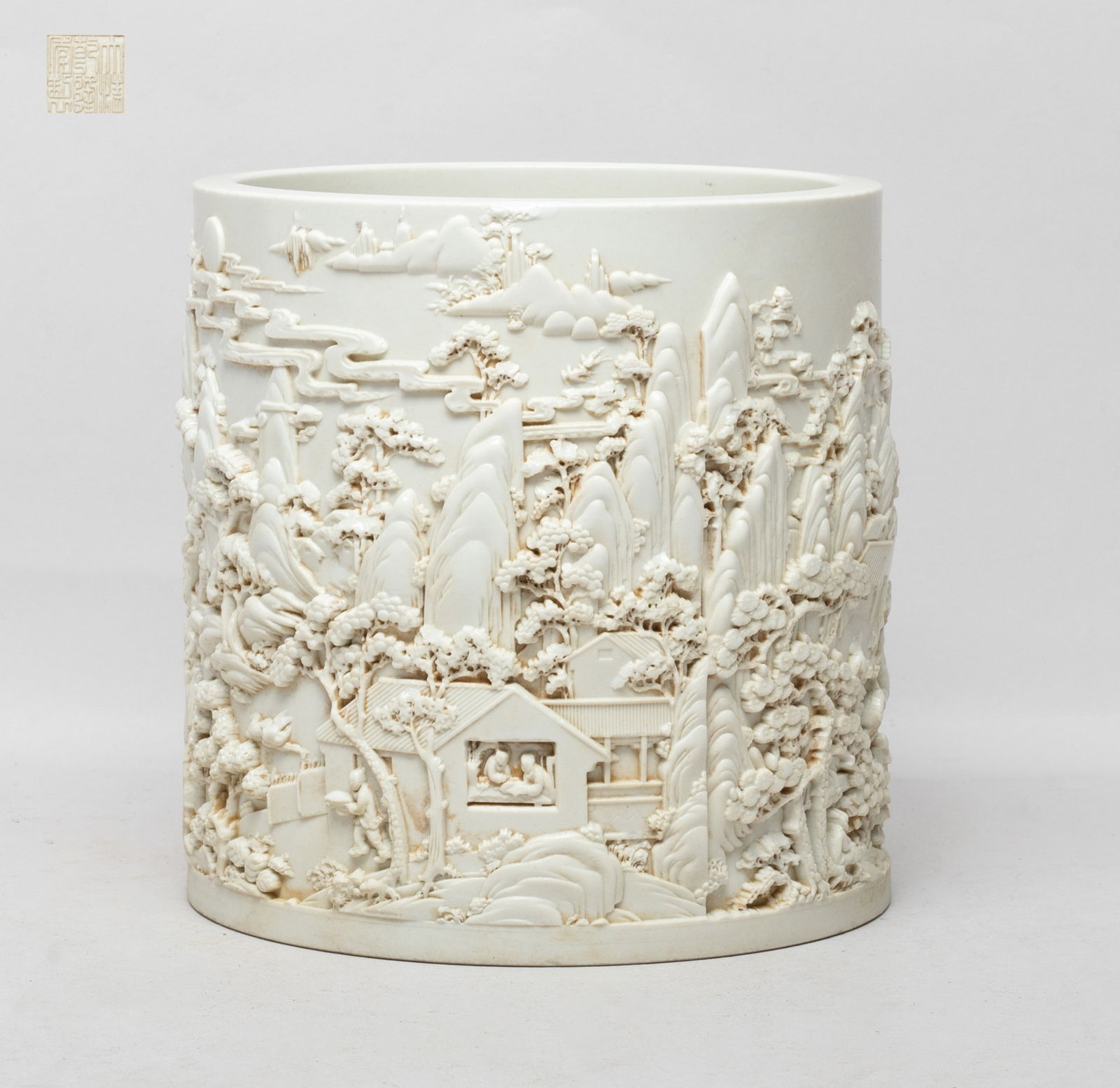 Chinese Blanc De Porcelain Brush Pot: Of cylindrical form, the exterior carved with mountainous landscape scene, the bottom inscribed with a six-character mark, overall covered with creamy white glaze. Approx. 6.5*6.2 inch.