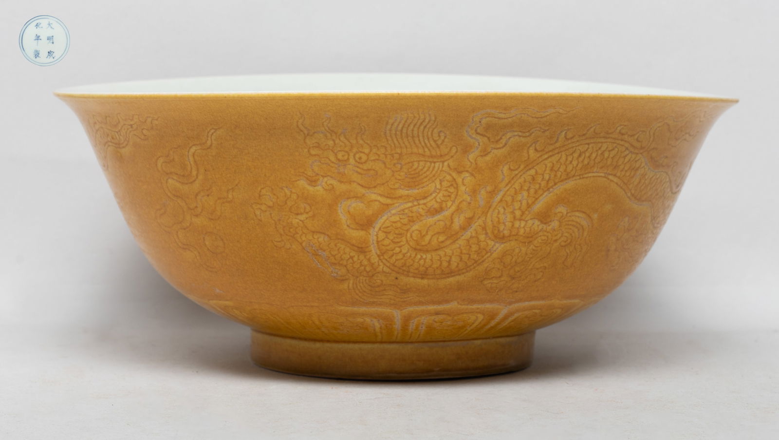 Chinese Export Rich Yellow Glazed Porcelain Bowl: The bowl carved in low relief with two sinuous dragons chasing flaming pearls, above a band of lappets, against crackled yellow glazed background, the bottom marked with six characters enclosed in dou