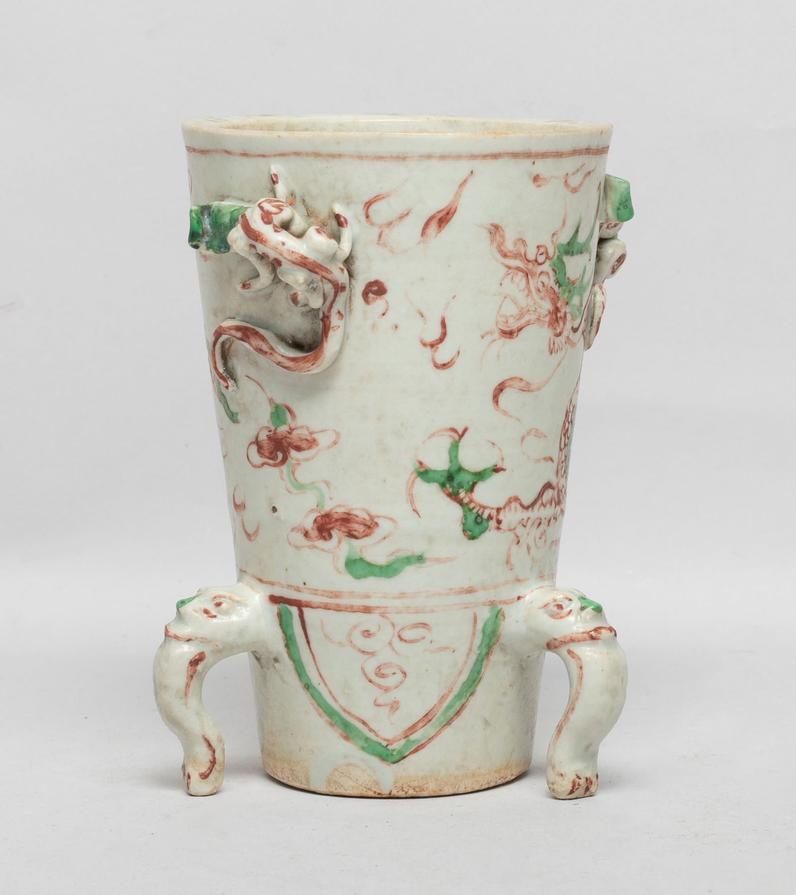 Chinese Red & Green Glazed Porcelain Tall Cup: Of tapered cylindrical form, the exterior painted in green and copper red colors above a band of leaves, flanked by two raised chilong and three feet issuing from beast masks. Approx. 4.7*3.9*3 inch.