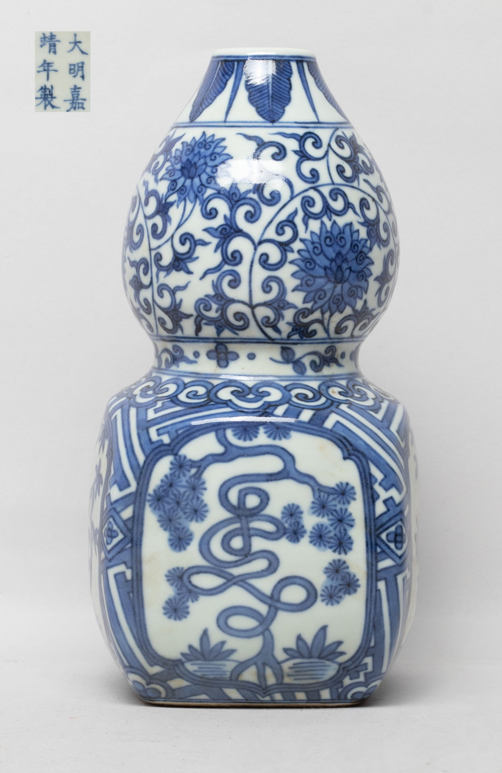 Estate Chinese Blue & White Porcelain Gourd Vase: Of double gourd shape, the upper bulb painted with leafy lotus scrolls, the lower bulb of square section, the sides painted with bamboo or pine tree, the bottom marked with six characters. Approx. 3.9