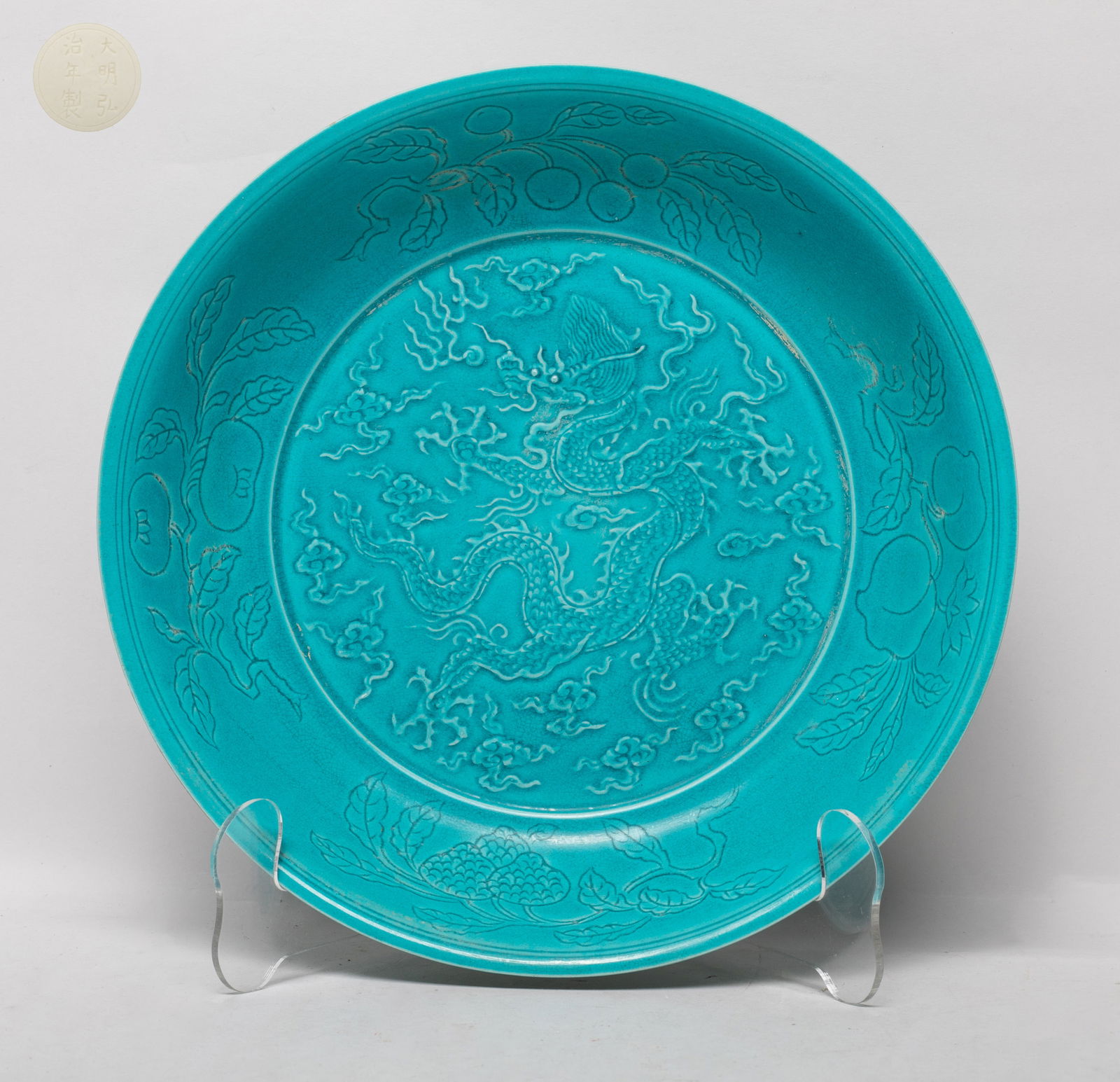 Chinese Green Glazed Porcelain Deep Plate: The plate interior centre carved with a five-clawed dragon pursuing a flaming pearl amidst clouds, the sides incised with various fruits, the exterior sides incised lotus, the inside and out turquoise