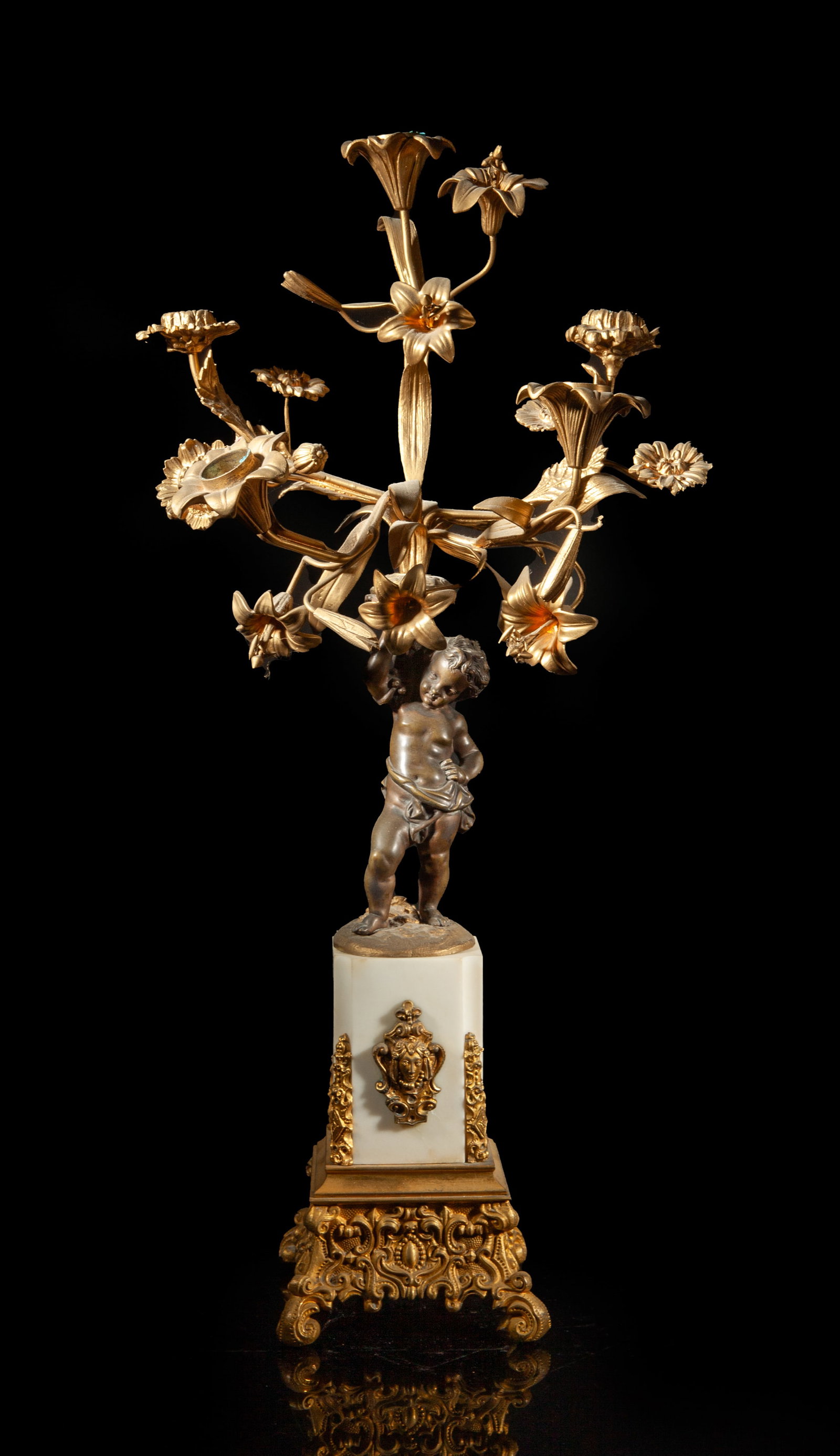 France Early 1900s Gilt & Marble Candelabra: Cast as a boy supporting a flower stem form candelabra with five arm candlestick holder, with a white marble stand and a gilt metal base. Approx. 23*11*7 inch.