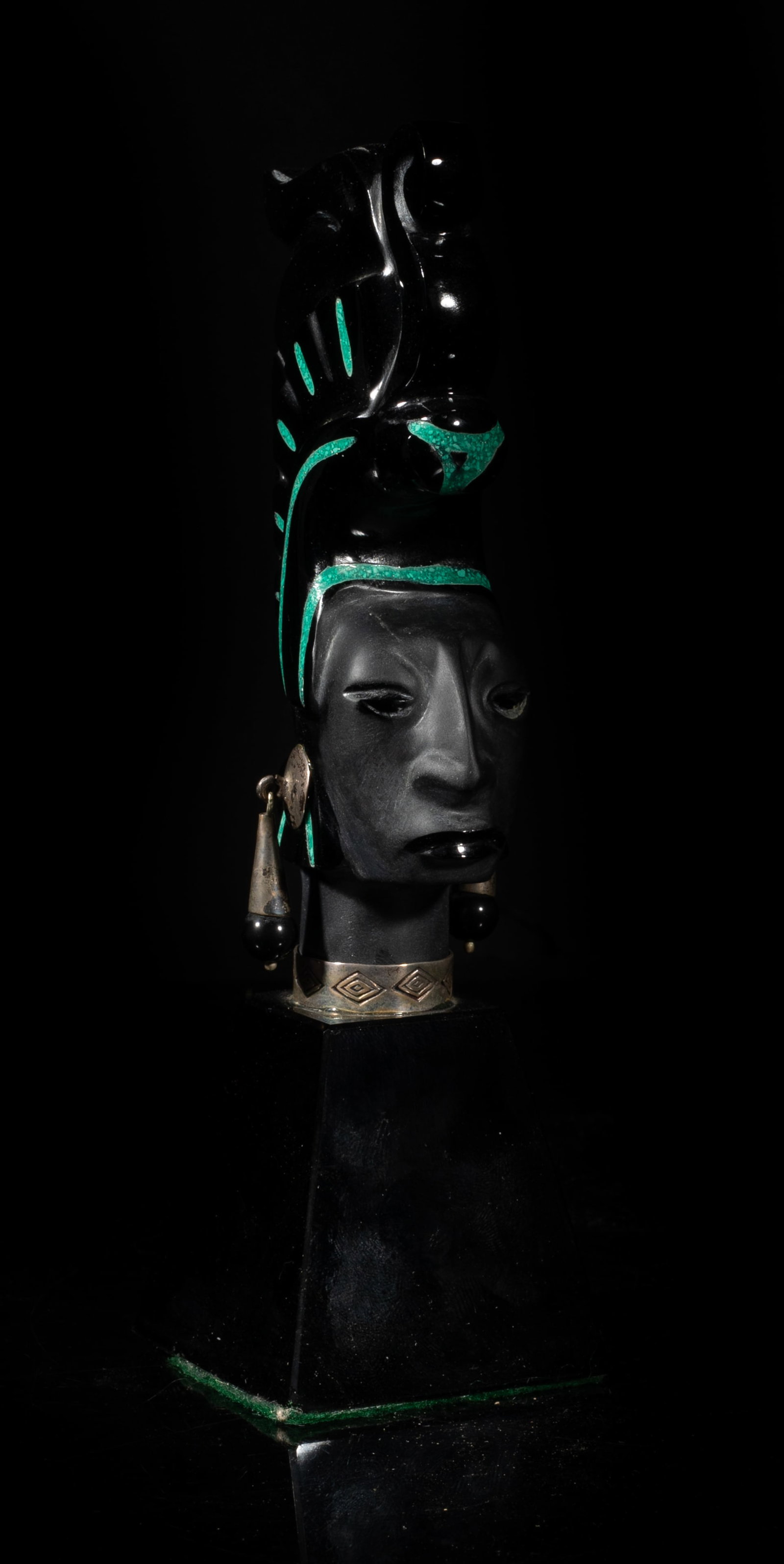 South American Sterling, Jet Stone Sculpture: South American type black jet stone sculpture carved as a female head wearing a tall hat and a pair of sterling earrings. Approx. 6.7*2.3*2 inch. The Estate of Hollywood, CA. 2009